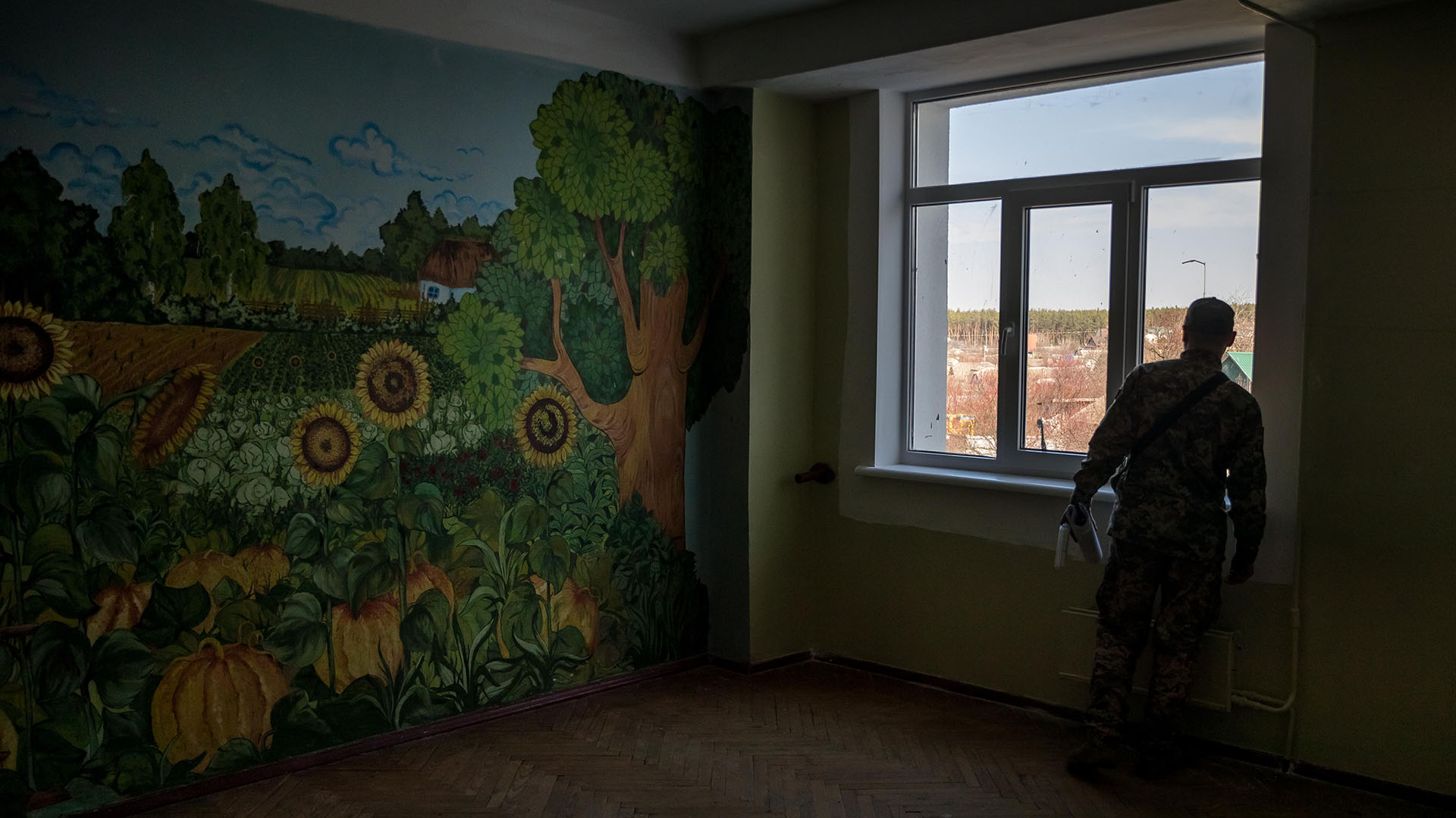 Fotografía del 15 de abril del 2022 que muestra a un voluntario asomándose por la ventana de un campo de entrenamiento ubicado en las inmediaciones de Kiev (Ucrania). EFE/ Miguel Gutiérrez
