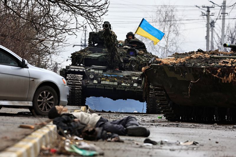 Soldados del ejército ucraniano sentados en la parte superior de su tanque mientras el cuerpo de un civil asesinado por soldados del Ejército ruso, yace en la calle, en la región de Kiev (REUTERS/Zohra Bensemra)