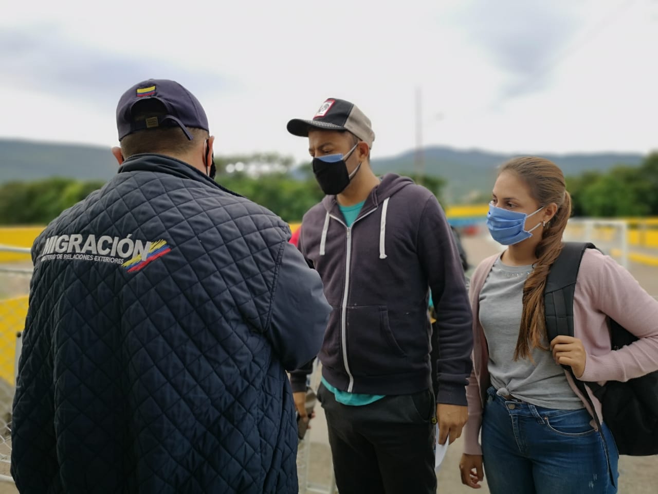 Funcionario de Migración Colombia revisa los documento de dos viajeros en la frontera Colombia - Venezuela. / Migración Colombia