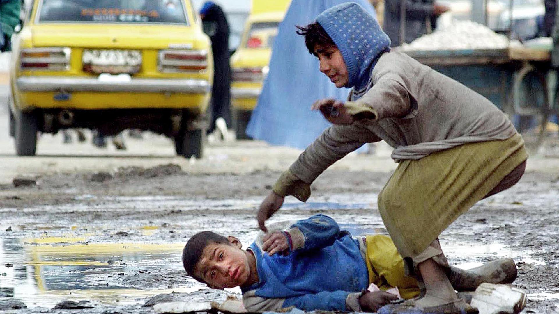 Un niño afgano yace en el suelo cubierto de nieve mientras mendiga en una calle de Kabul, el 24 de febrero de 2003. Afganistán, devastado por décadas de guerra, se encuentra entre los países más pobres de Asia. (AFP / JOYA SAMAD)