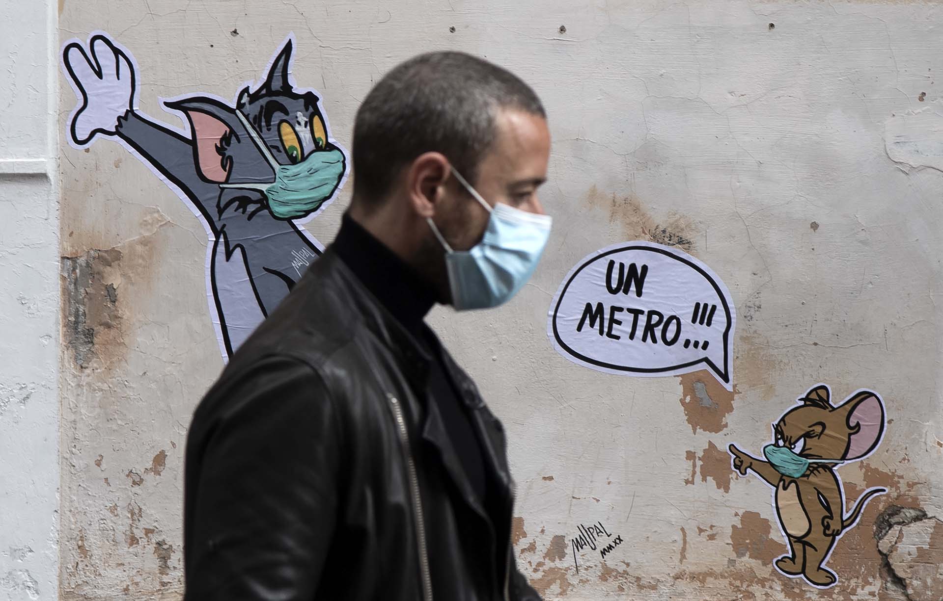 Un hombre pasa frente a un mural del artista Maupal que homenajea a los legendarios Tom y Jerry en una calle de Roma.