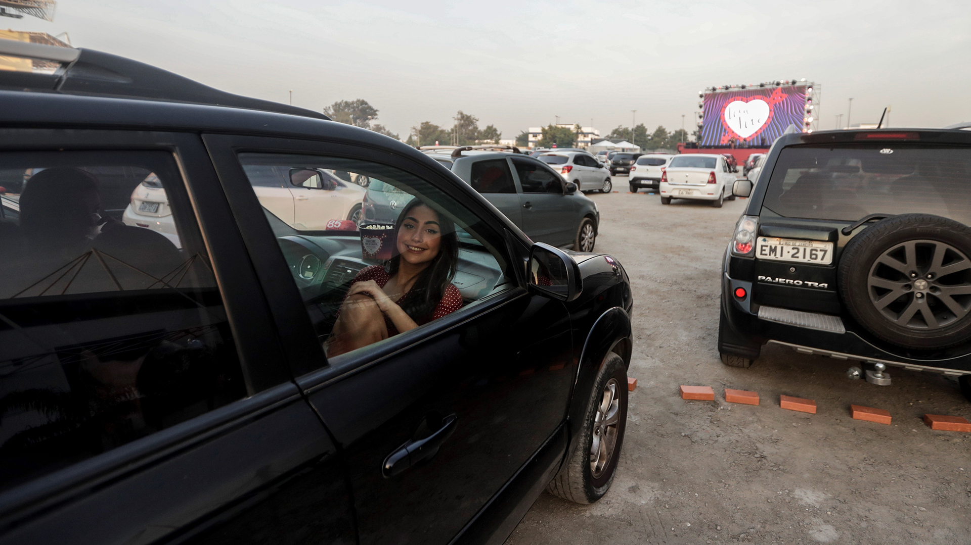 Una mujer espera en un auto la proyección de una película en el Love Cine Drive-in Theater, ubicado en el estacionamiento del Jeunesse Arena, en Río de Janeiro (EFE/Antonio Lacerda)
