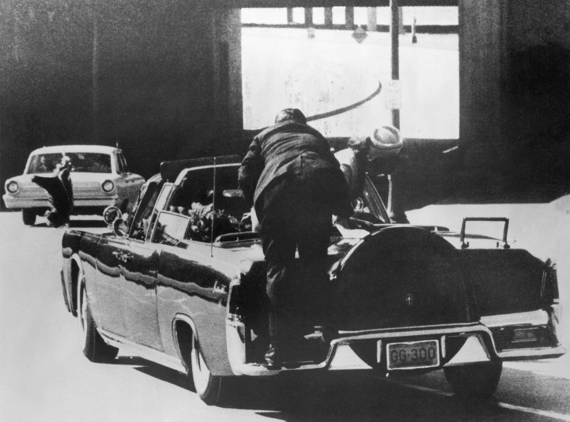Asesinato de John F. Kennedy. La Sra. Kennedy se inclina sobre el Presidente baleado mientras un hombre del Servicio Secreto sube a la parte trasera del auto en Dallas, Texas, el 22 de noviembre de 1963 (Bettmann Archive)