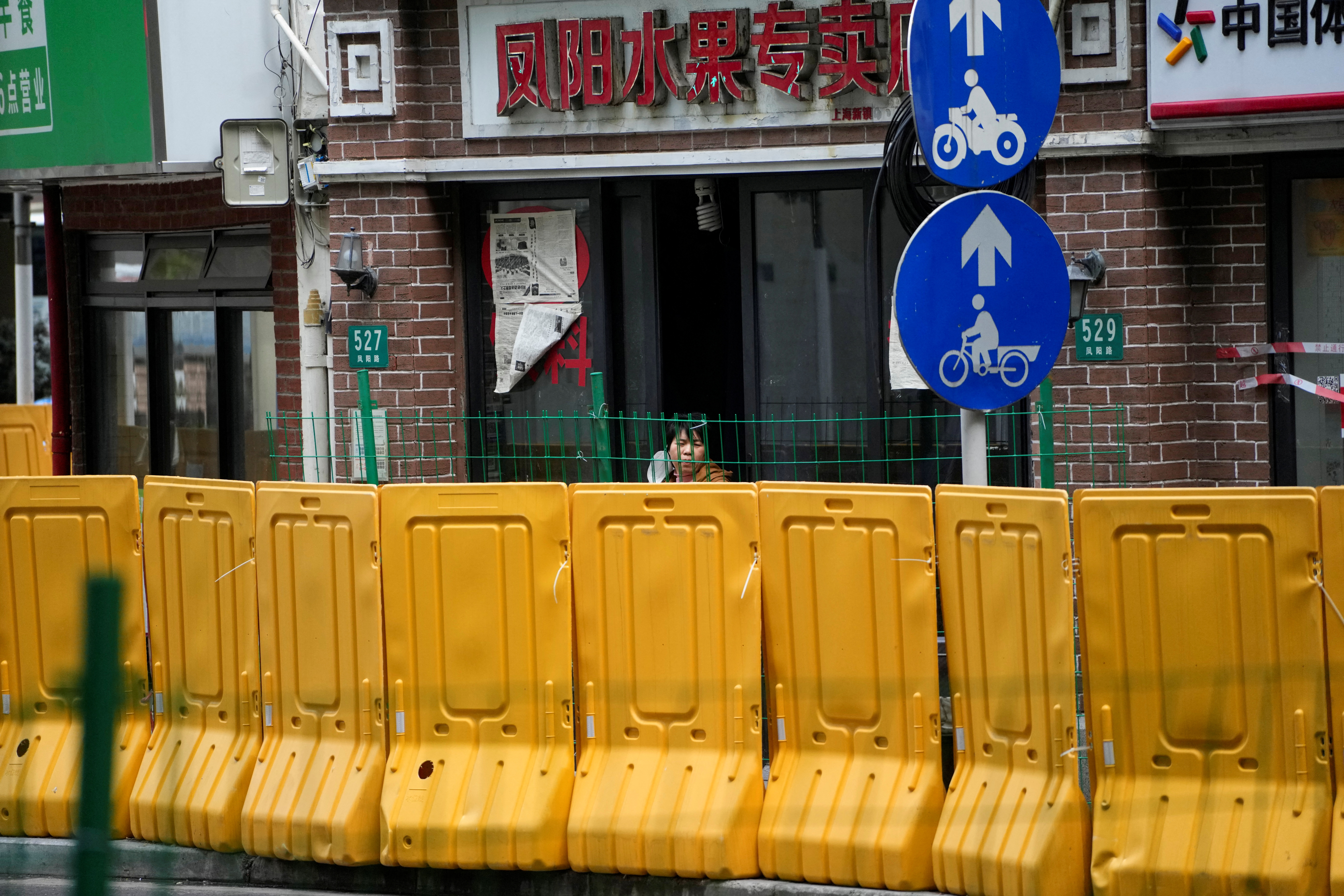 Un residente mira detrás de las barreras en una frutería, durante el cierre, en medio de la pandemia de la enfermedad por coronavirus (COVID-19), en Shanghái, China, el 16 de mayo de 2022. REUTERS/Aly Song