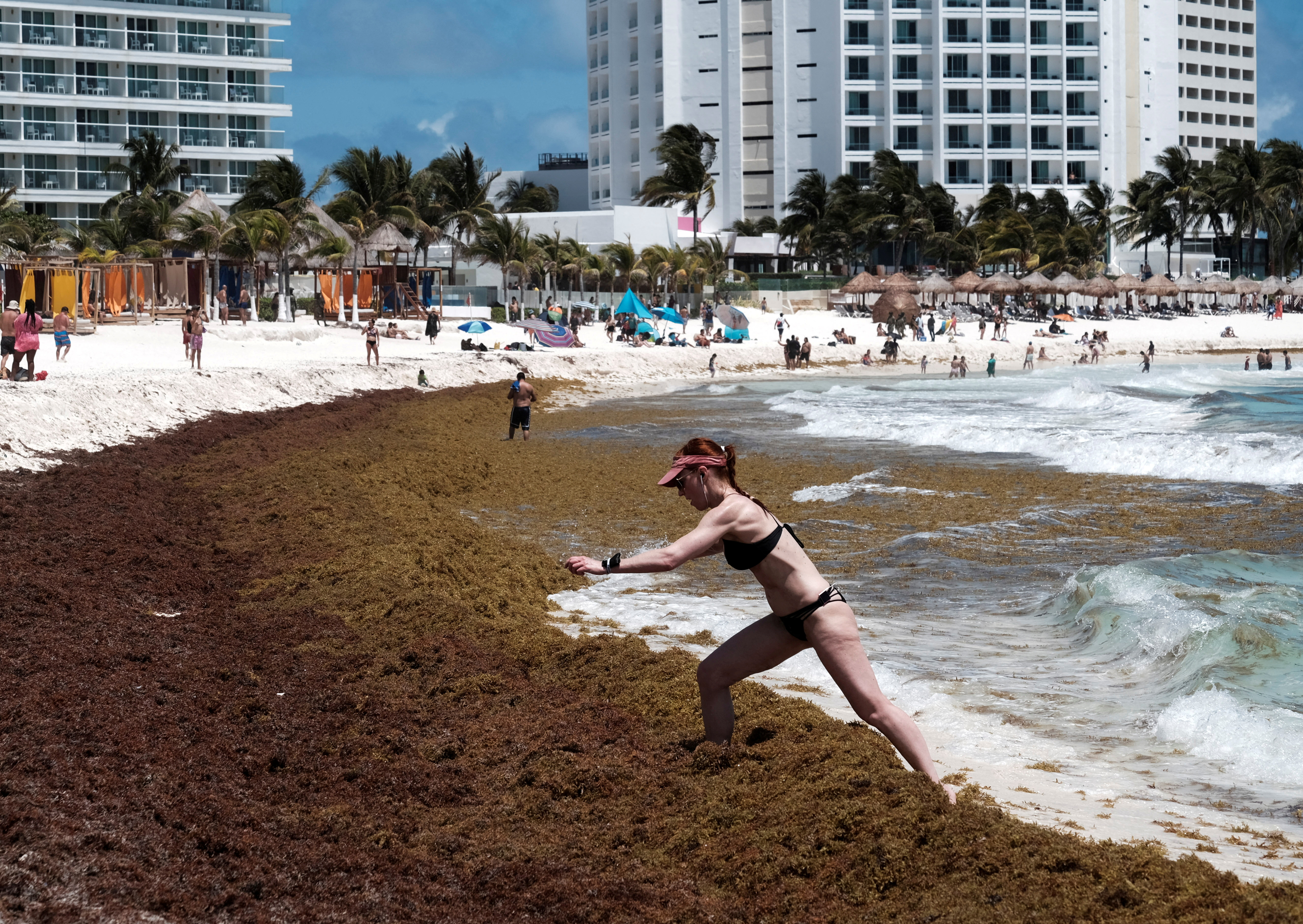 Un turista camina a través de una acumulación de algas sargazo en la playa Gaviota Azul en Cancún, México 3 de abril de 2022. REUTERS/Paola Chiomante/Archivo