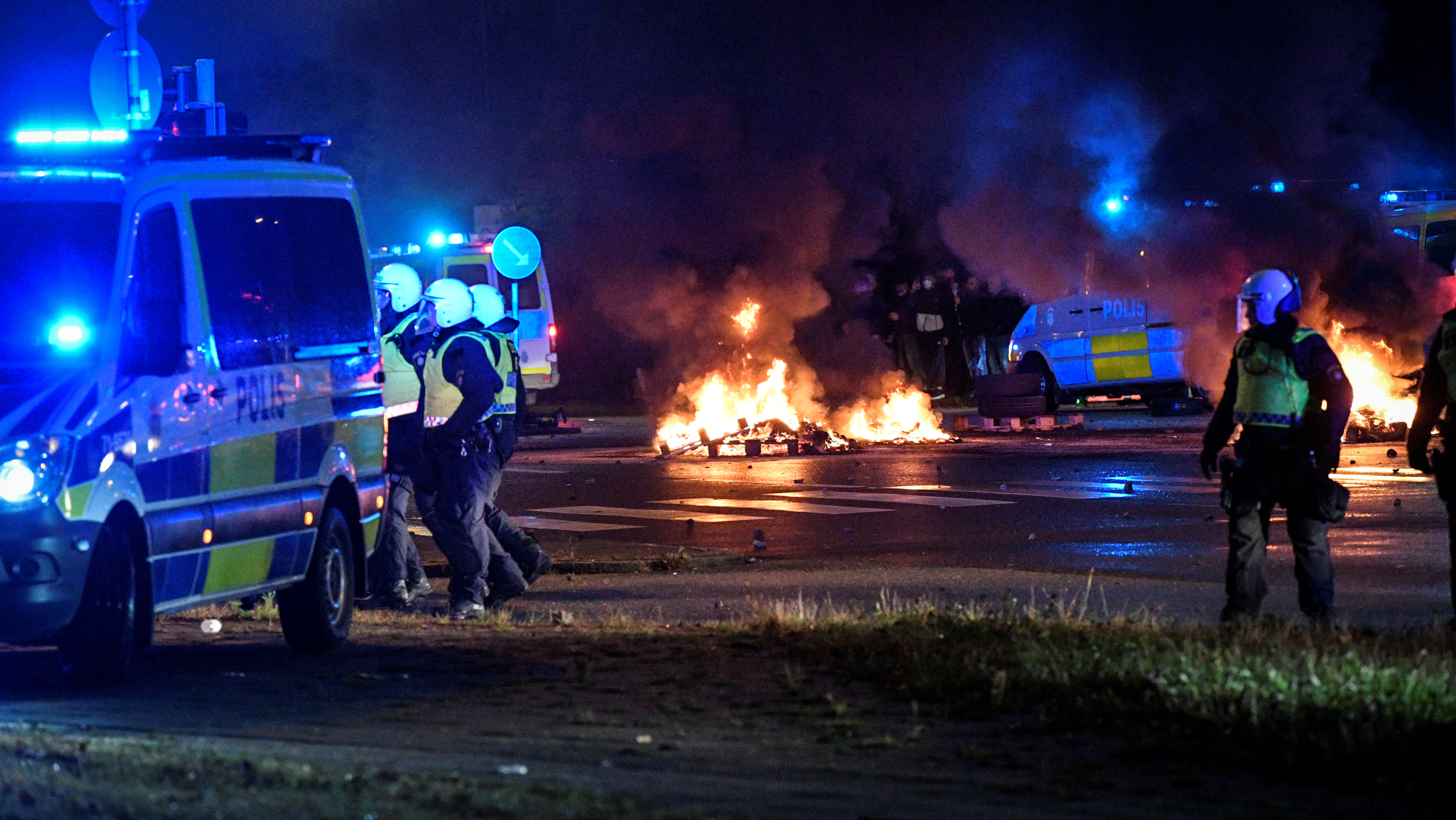 Agentes de policía caminan cerca de neumáticos en llamas durante los disturbios en Malmo (Agencia de noticias TT vía REUTERS)