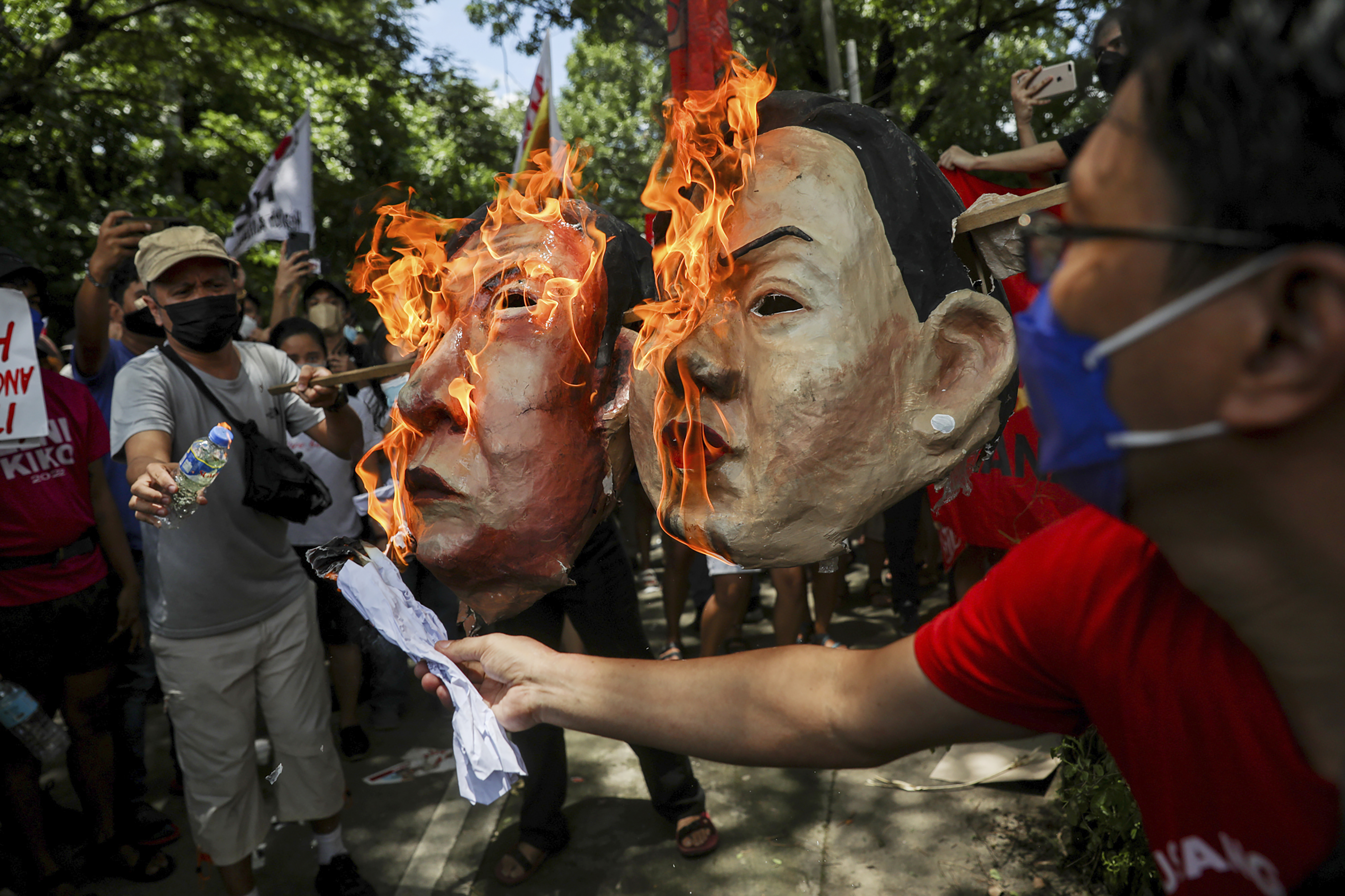 Activistas queman máscaras de Ferdinand "Bongbong" Marcos Jr. y de su compañera de fórmula Sara Duterte, hija del actual presidente, durante una manifestación en la Comisión de Derechos Humanos en Ciudad Quezón. (Foto AP/Basilio Sepe)