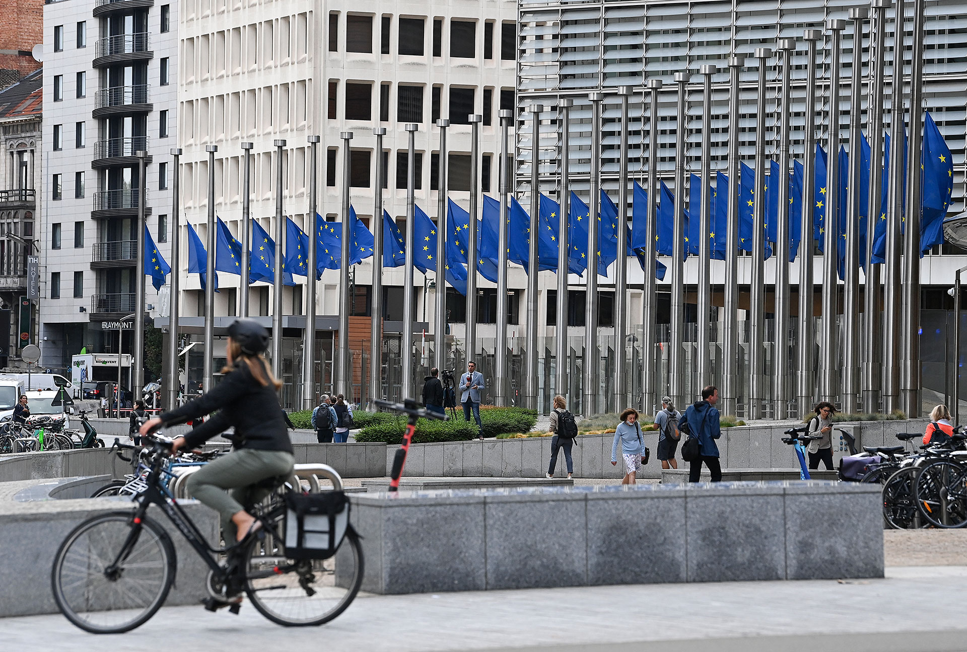 Un ciclista pasa junto a banderas europeas ondeando a media asta durante una reunión de ministros de energía de la UE en Bruselas (JOHN THYS / AFP)