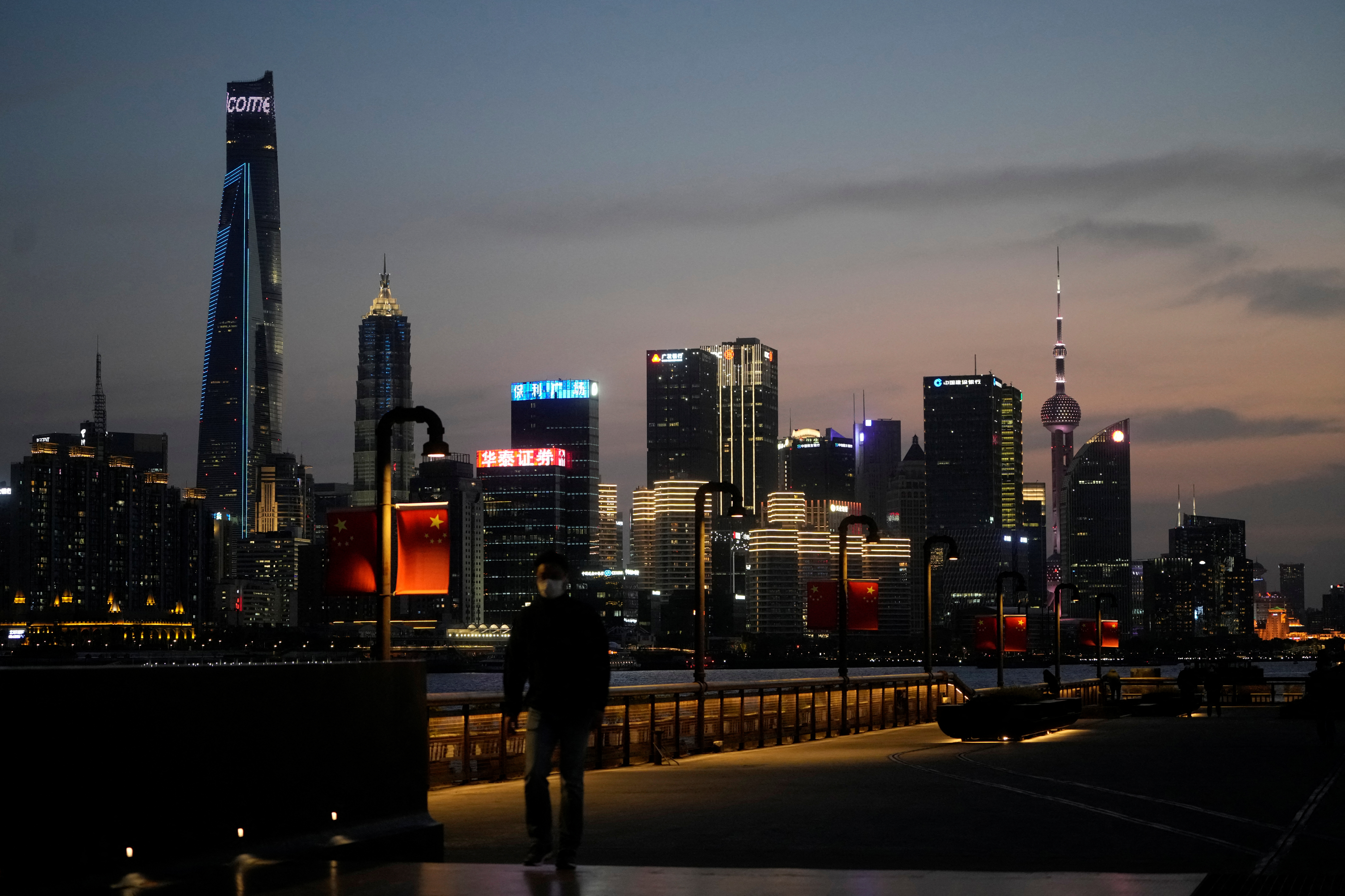 Un hombre camina frente al distrito financiero de Lujiazui, visto al otro lado del río Huangpu al atardecer, en medio del cierre en Pudong. (REUTERS/Aly Song)
