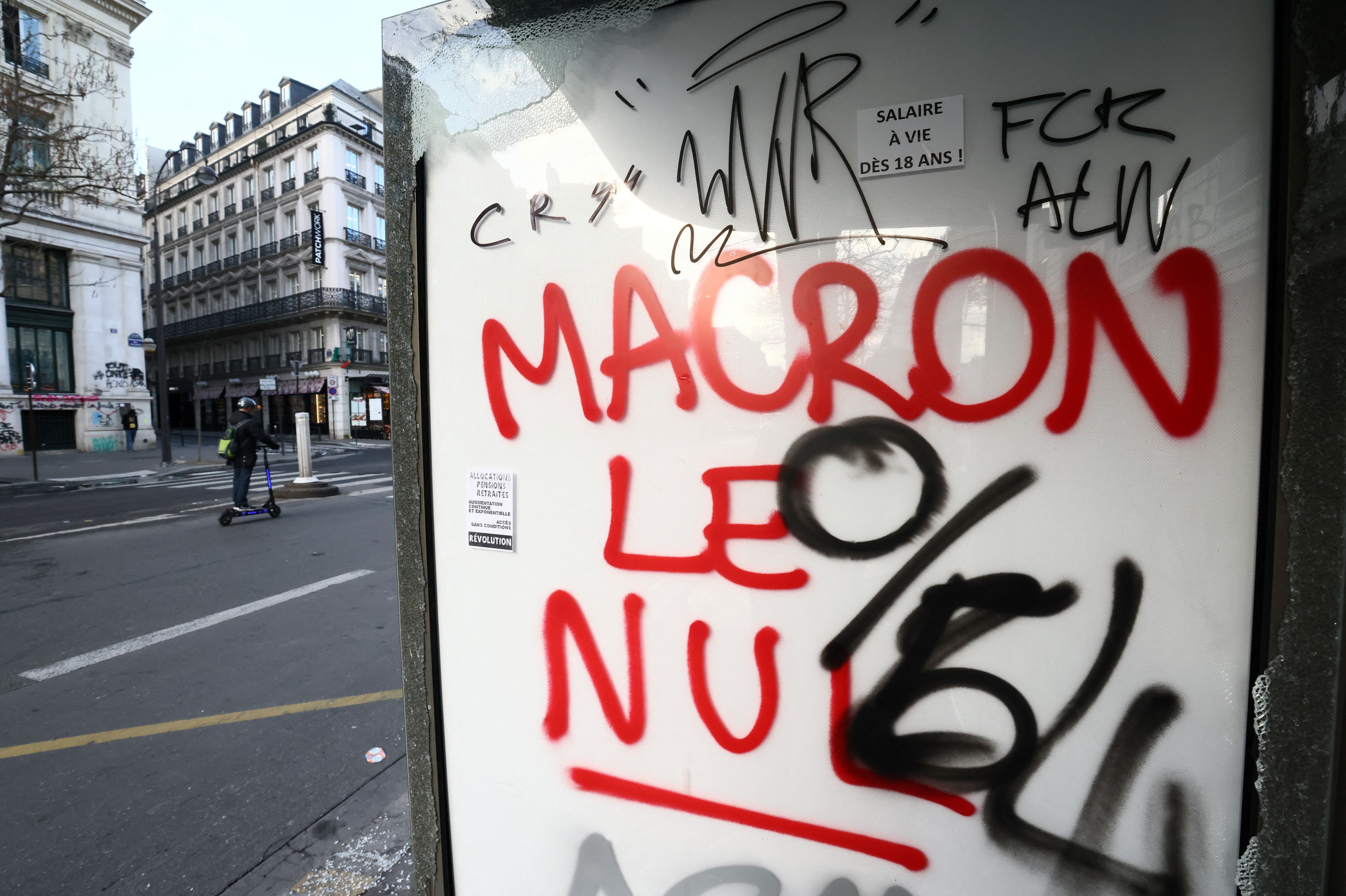 "Macron, el inútil": un graffitti sobre una publicidad callejera destruida en París, tras los disturbios del jueves (REUTERS/Yves Herman)