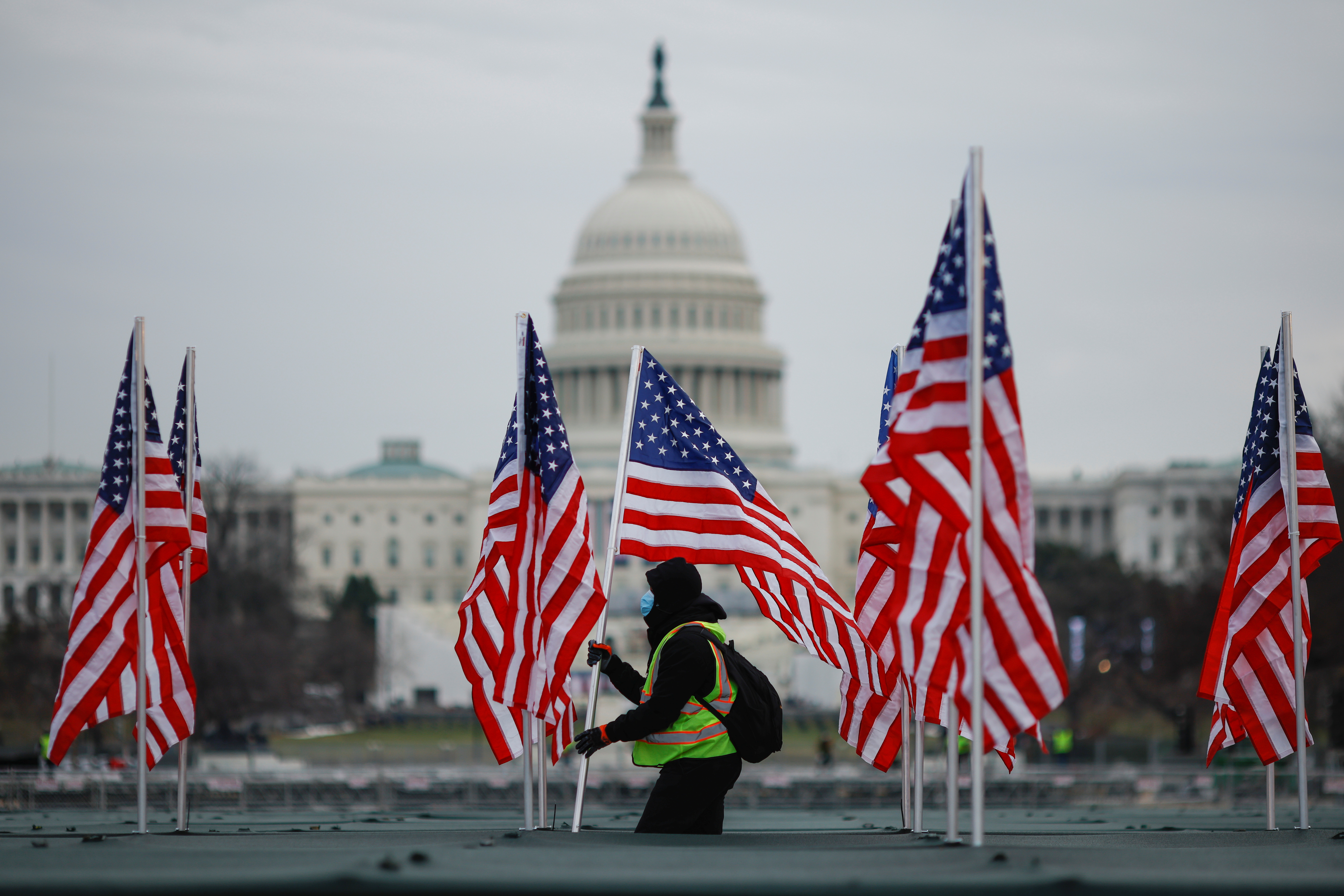 Un trabajador instala una bandera de los Estados Unidos para exhibirla en el National Mall, como parte del homenaje que prepare Biden para las víctimas de coronavirus en el país. REUTERS / Carlos Barria