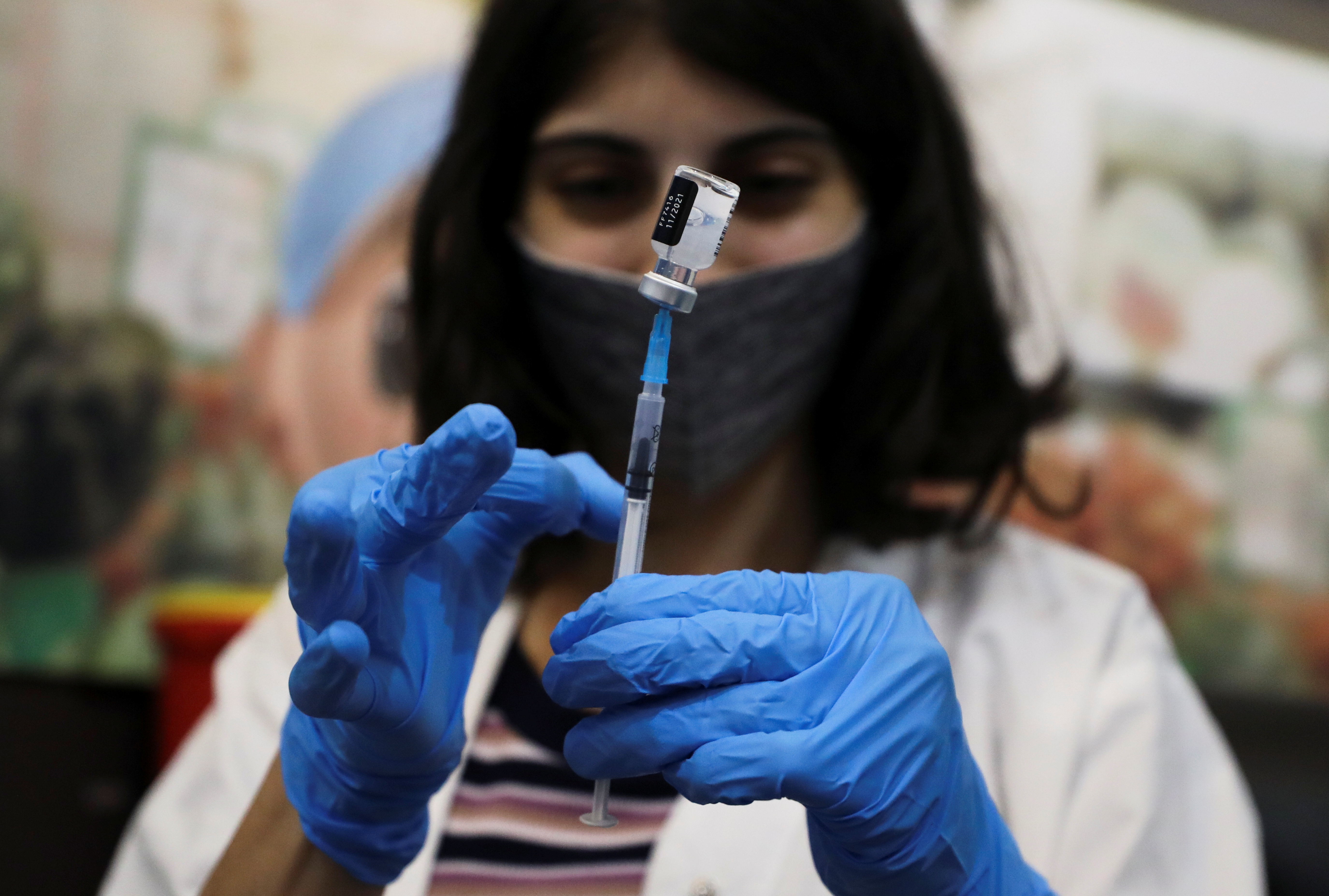 Una trabajadora médica se prepara para administrar la tercera dosis de la vacuna contra la enfermedad por coronavirusa un paciente en la Organización de Mantenimiento de la Atención Médica Clalit en Jerusalén (REUTERS)