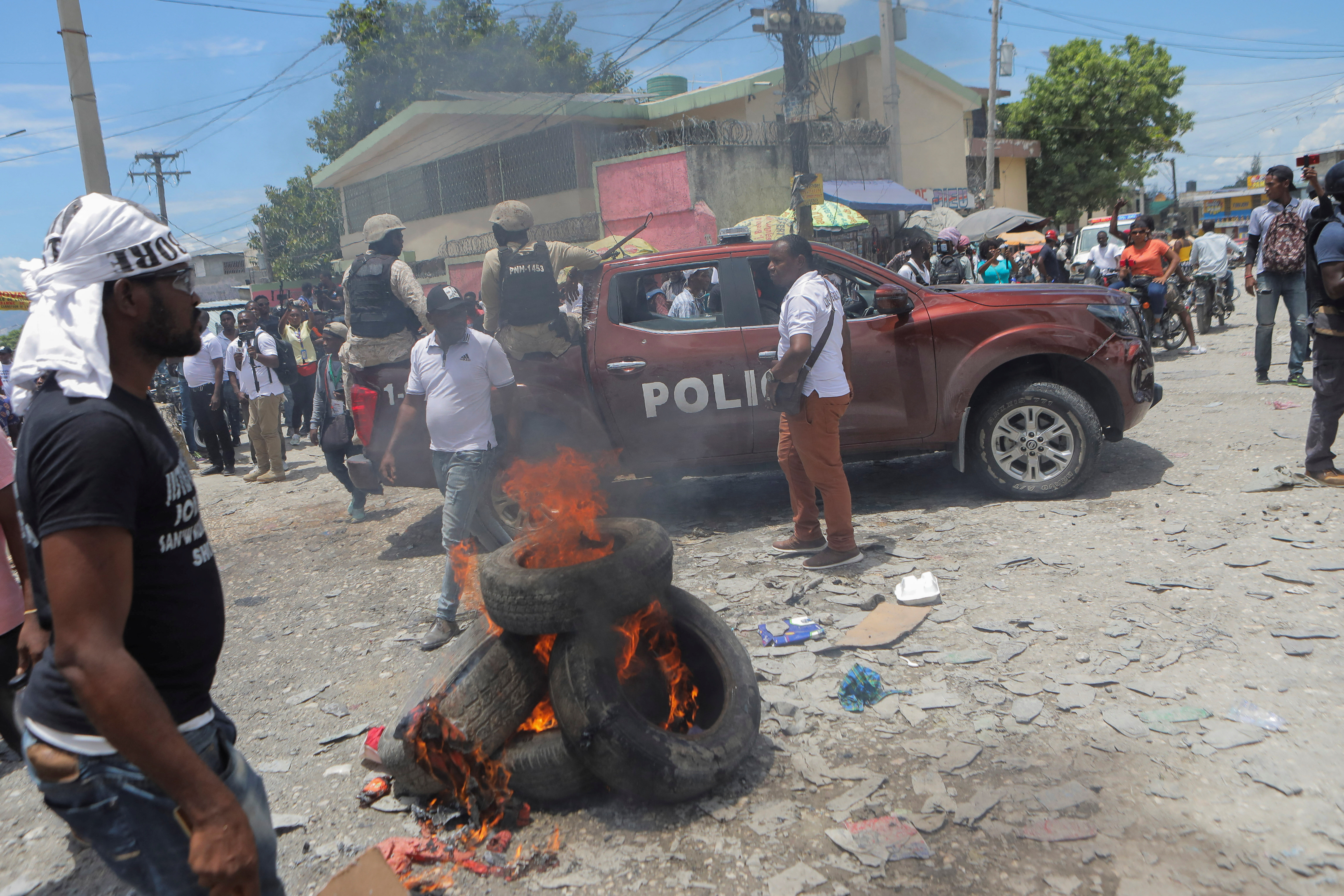 Policías y manifestantes se reúnen alrededor de un bloqueo de carretera en llamas durante una protesta para exigir justicia para el presidente Jovenel Moise un año después de su asesinato, en Puerto Príncipe, Haití, el 7 de julio de 2022. REUTERS/Ralph Tedy Erol