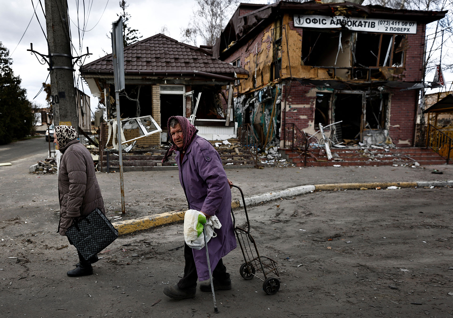 Dos mujeres pasan frente a las tiendas destruidas por los bombardeos rusos

