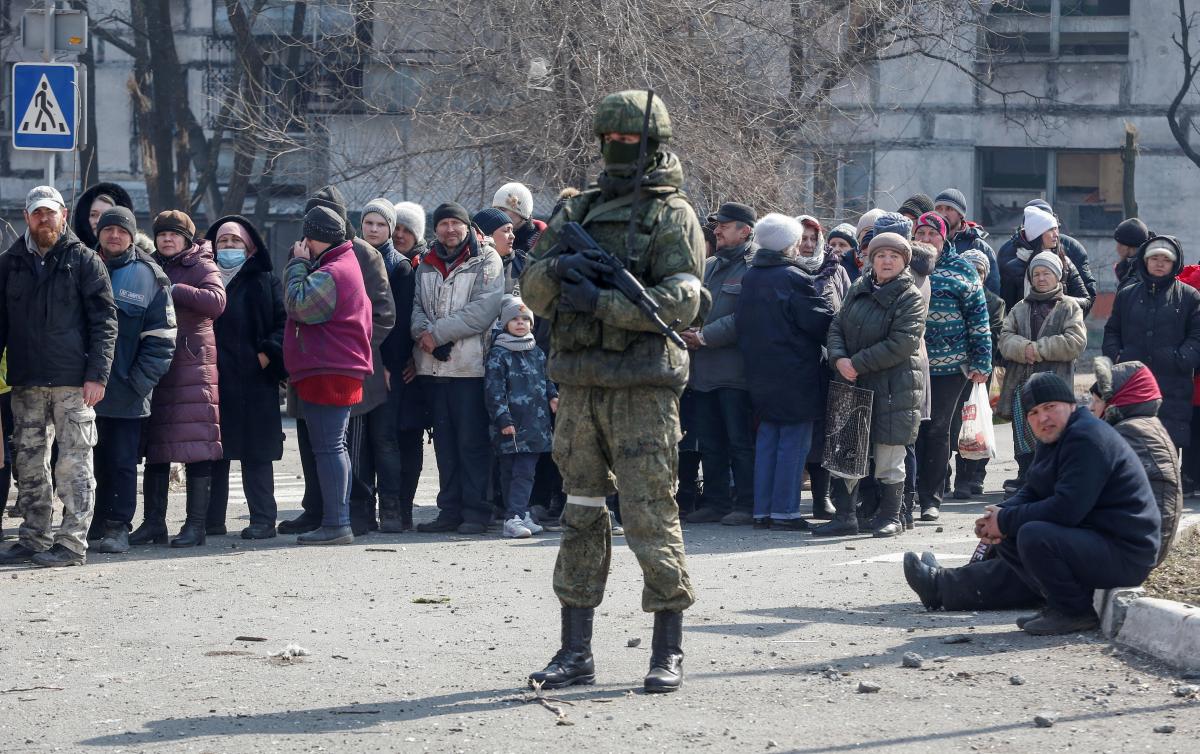 Un soldado ruso custodia una cola de personas en la ocupada Melitopol, donde se registra una intensa resistencia por parte de grupos de partisanos locales. (Reuters)