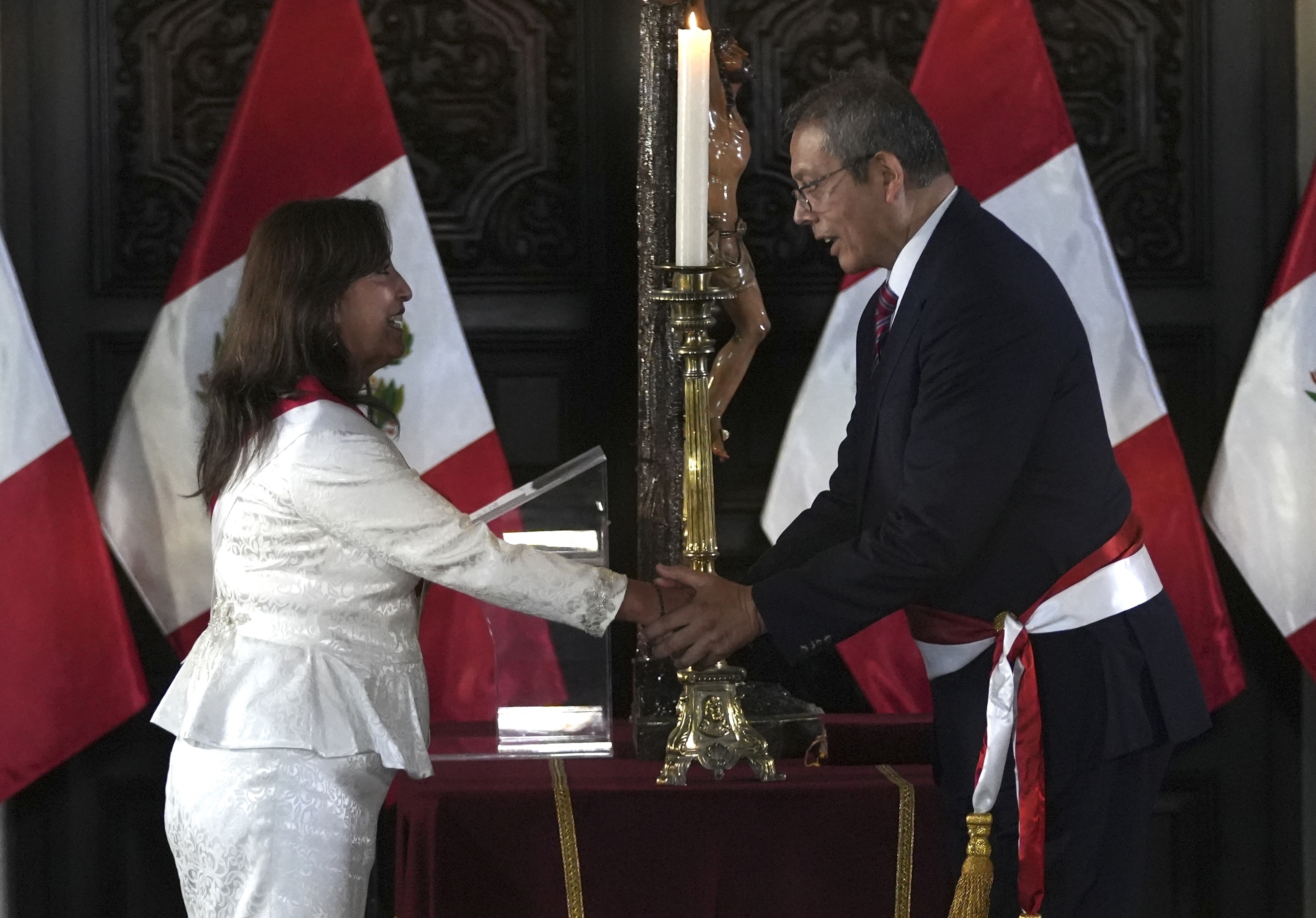 Dina Boluarte estrecha la mano de su jefe de gabinete Pedro Angulo durante la juramentación de sus ministros en el Palacio de Gobierno. (AP Foto/Guadalupe Pardo)