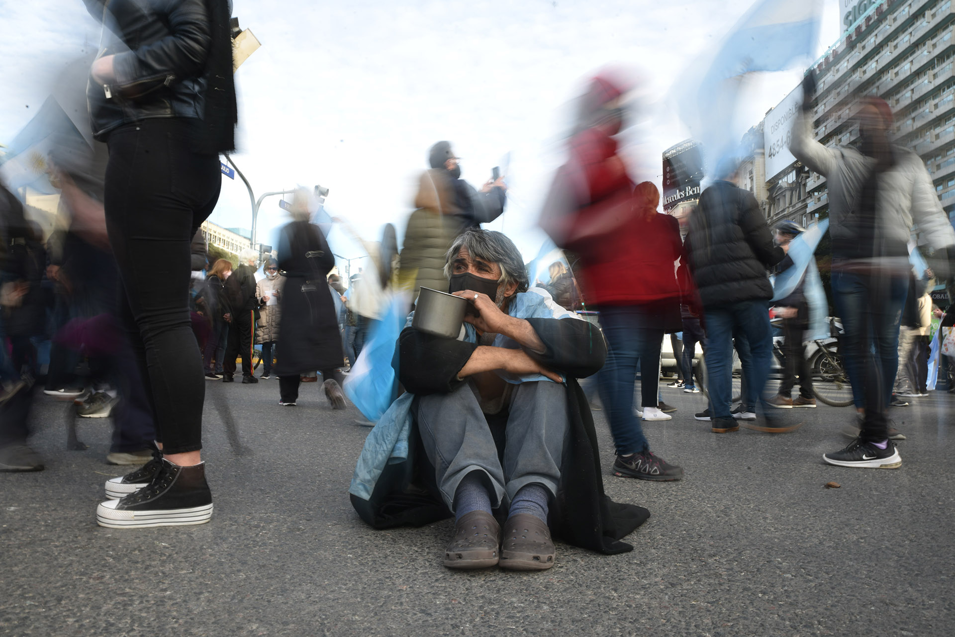 Un hombre pide limosna en el medio de la protesta
