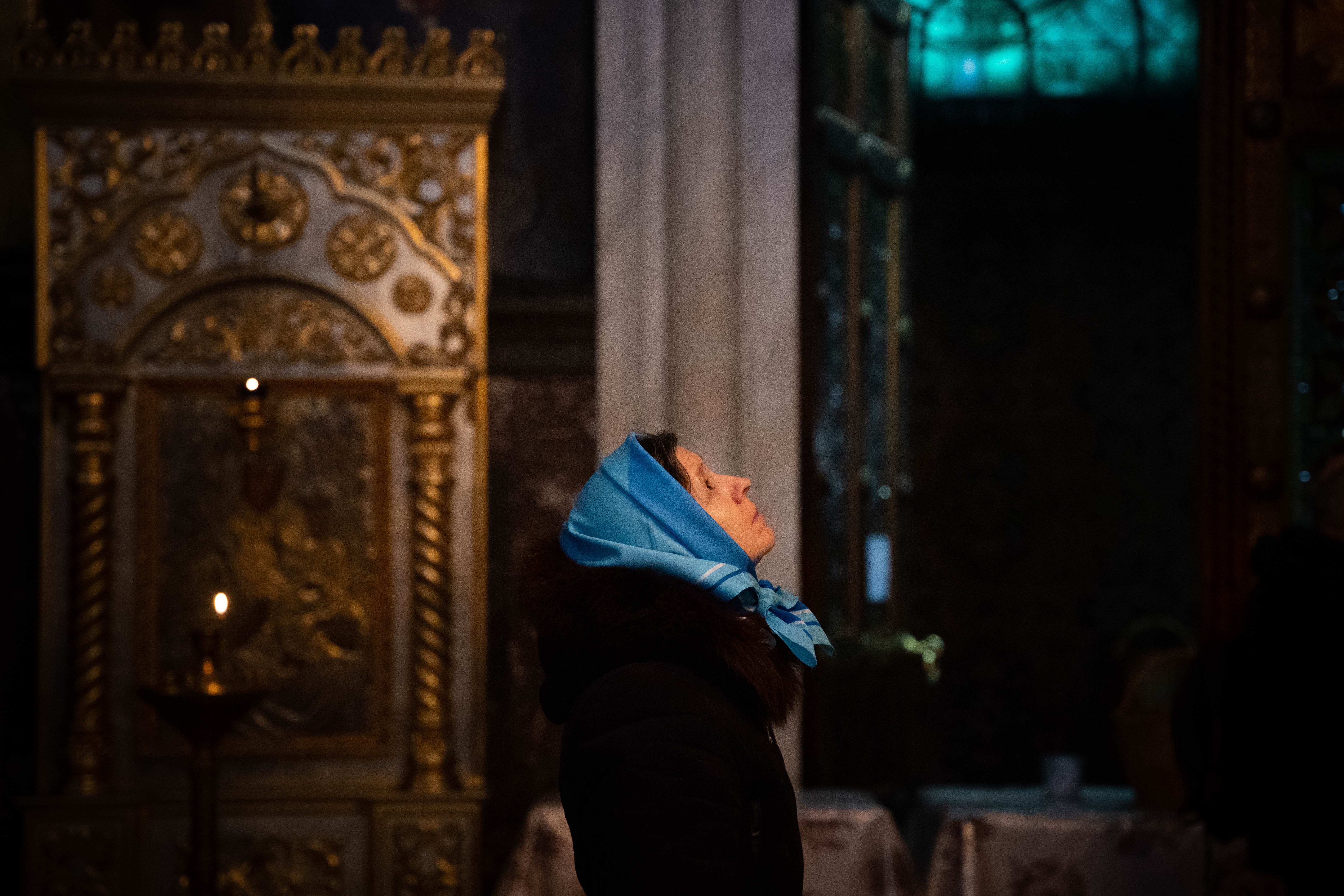Una mujer mira al cielo mientras participa de la misa que se celebra todos los domingos en la Catedral de San Vladimir.