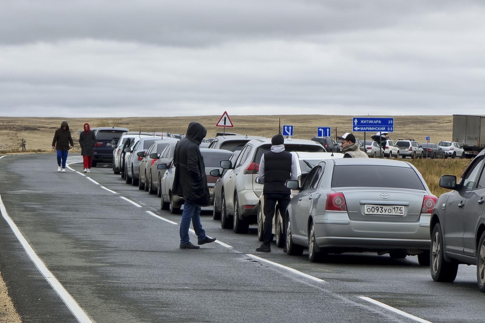 Varias personas caminan junto a sus coches esperando para cruzar a Kazajstán en el paso fronterizo de Mariinsky. Miles de rusos en edad de alistarse huyeran al extranjero. (AP, archivo)