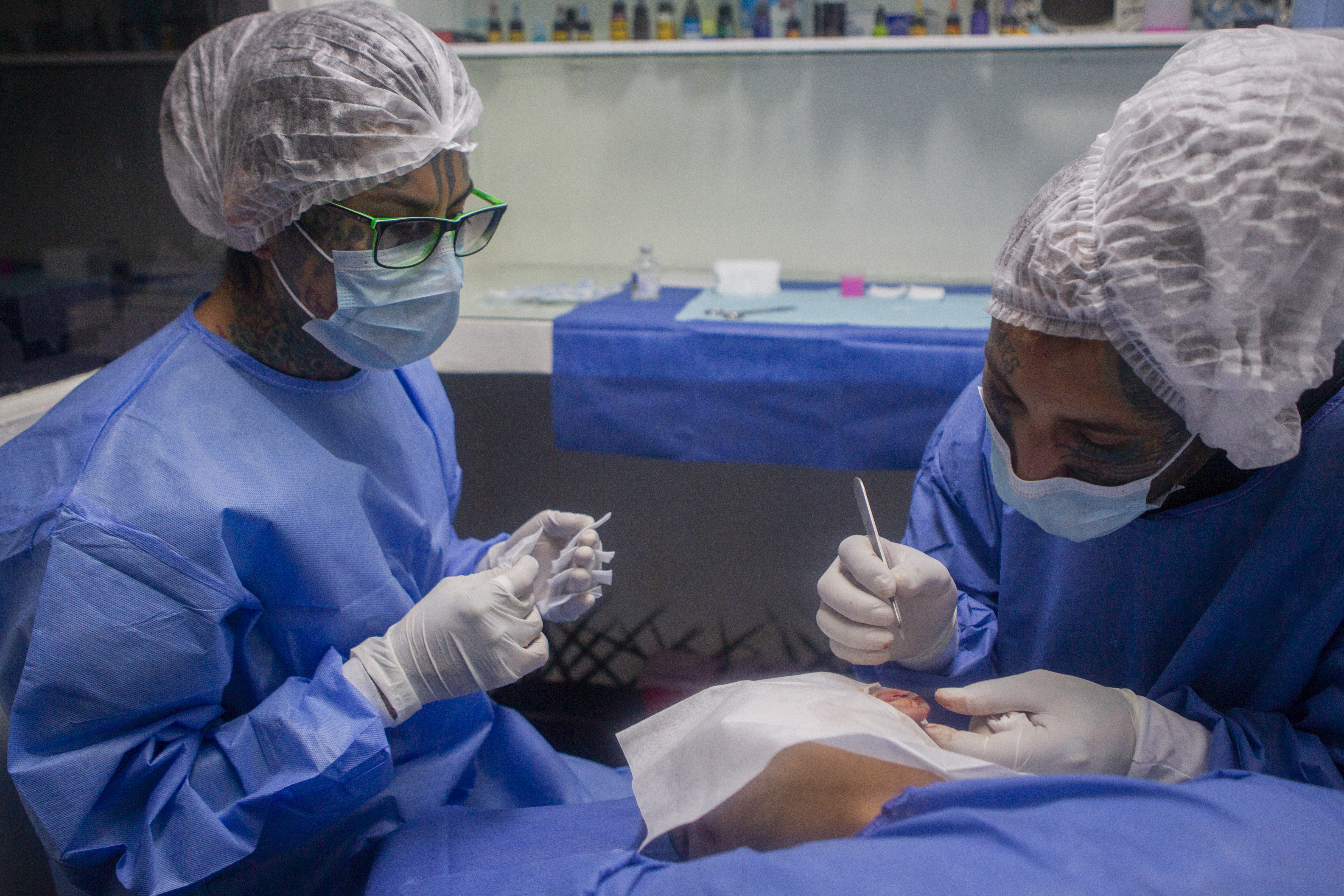 "Plaga" siendo asistido por "Cent" mientras realiza el corte de un fragmento de la oreja.
Noviembre 29, 2021
Foto: Karina Hernández / Infobae