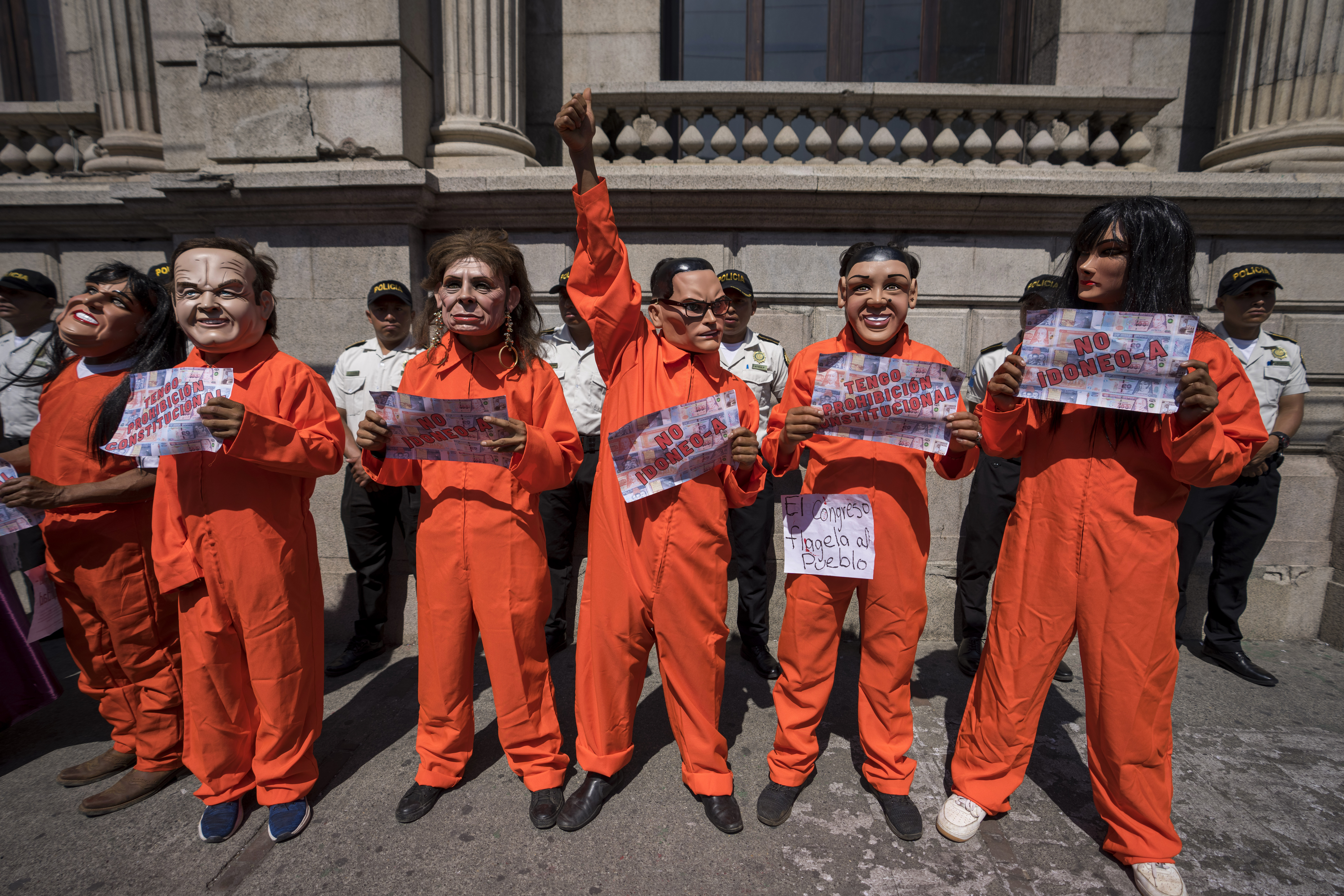 Manifestantes con disfraces y máscaras de prisioneros, para simbolizar a los políticos y candidatos presidenciales encarcelados, protestan frente al Congreso en la Ciudad de Guatemala  (AP Foto/Moisés Castillo)