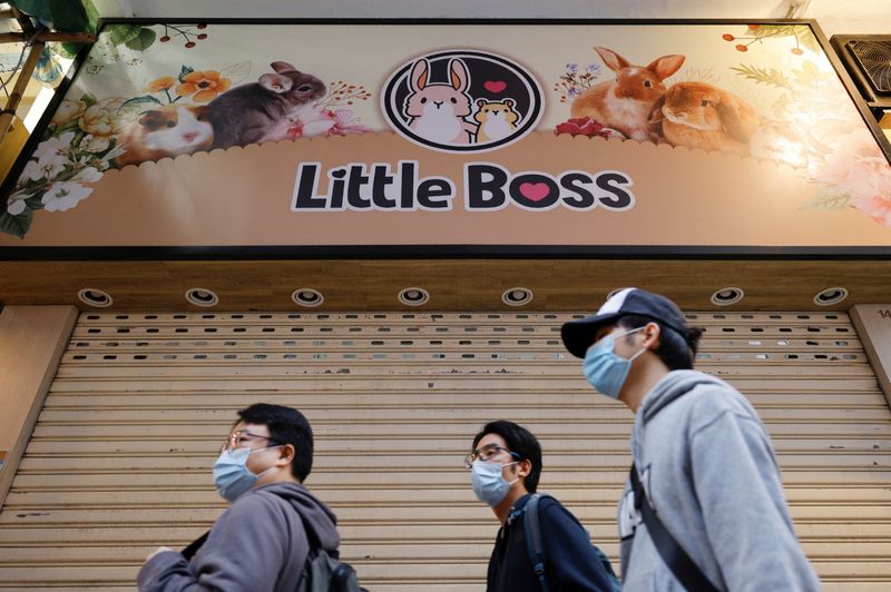 Tres personas con mascarilla frente a una tienda de mascotas cerrada, tras el anuncio del Gobierno hongkonés de que se sacrificarán unos 2.000 hámsteres tras un posible primer caso de contagio de animal a humano de COVID-19, en Hong Kong, el 18 de enero de 2022. REUTERS/Tyrone Siu