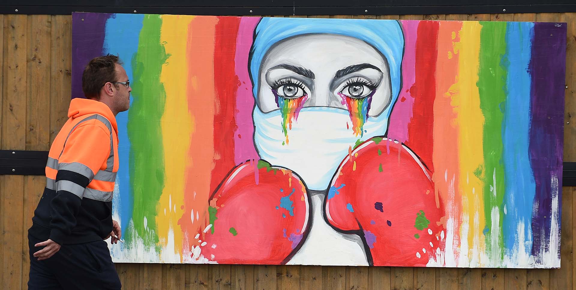 Un hombre pasa frente a un mural de la artista Rachel List en tributo a los trabajadores del servicio público de salud del NHS en Pontefract, al norte de Inglaterra.