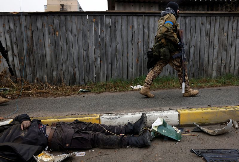 Un soldado ucraniano pasa junto al cuerpo de un civil, en Bucha.(REUTERS/Zohra Bensemra)