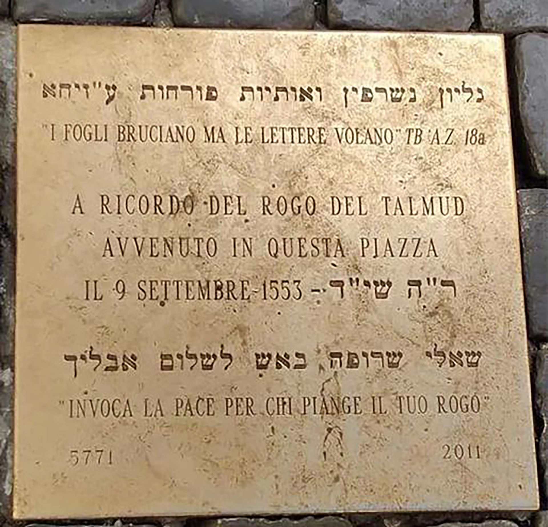 Otra pequeña placa de bronce, colocada en la plaza en el 2011, que recuerda que en ese lugar el 9 de septiembre de 1553, el papa Paulo IV, Gian Pietro Cafara, ordenó quemar todos los Talmud que hubiera en Roma
