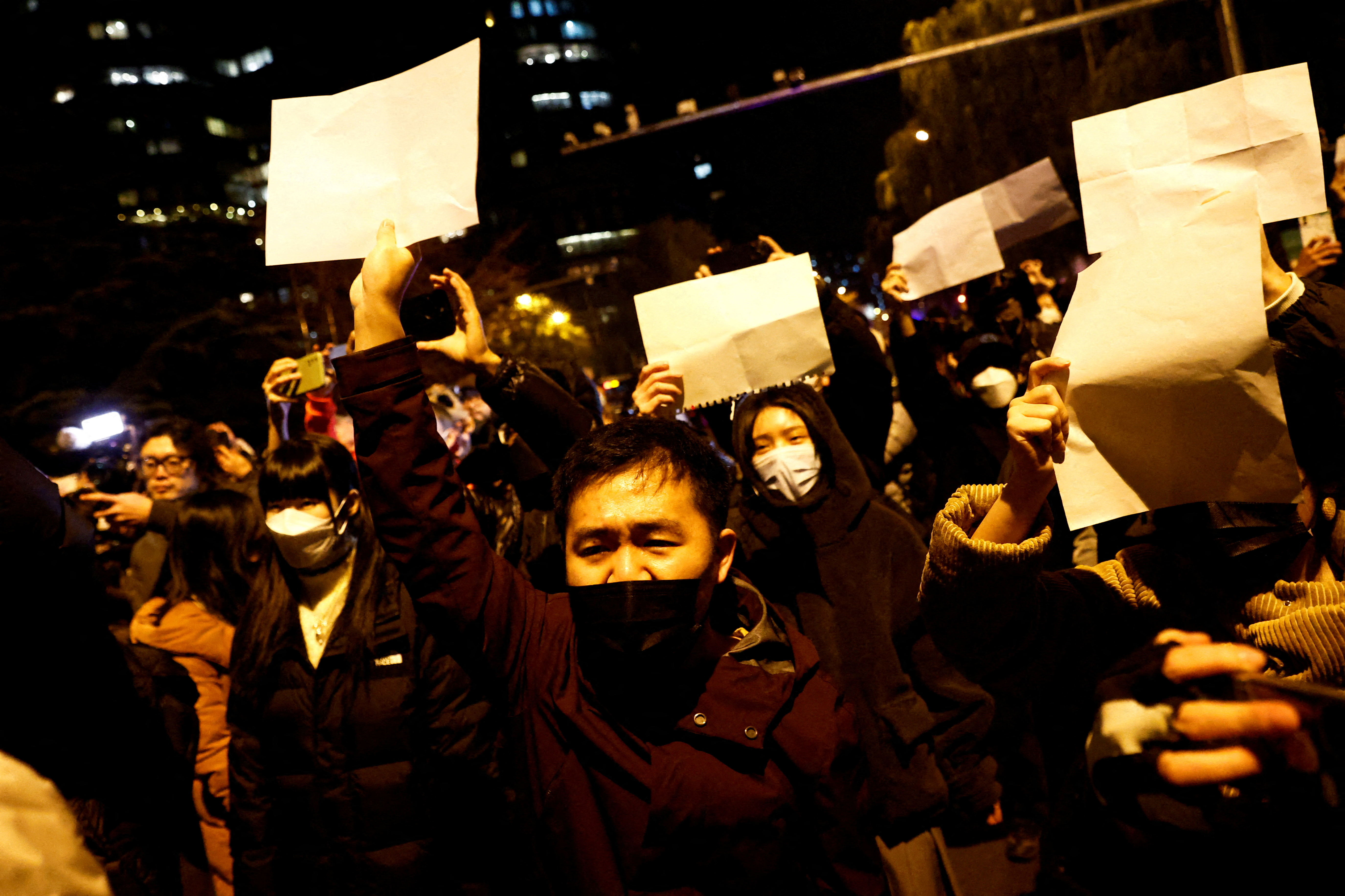 Ciudadanos chinos se reúnen para una vigilia y sostiene hojas de papel blancas en protesta por las restricciones de la enfermedad por coronavirus (COVID-19)
