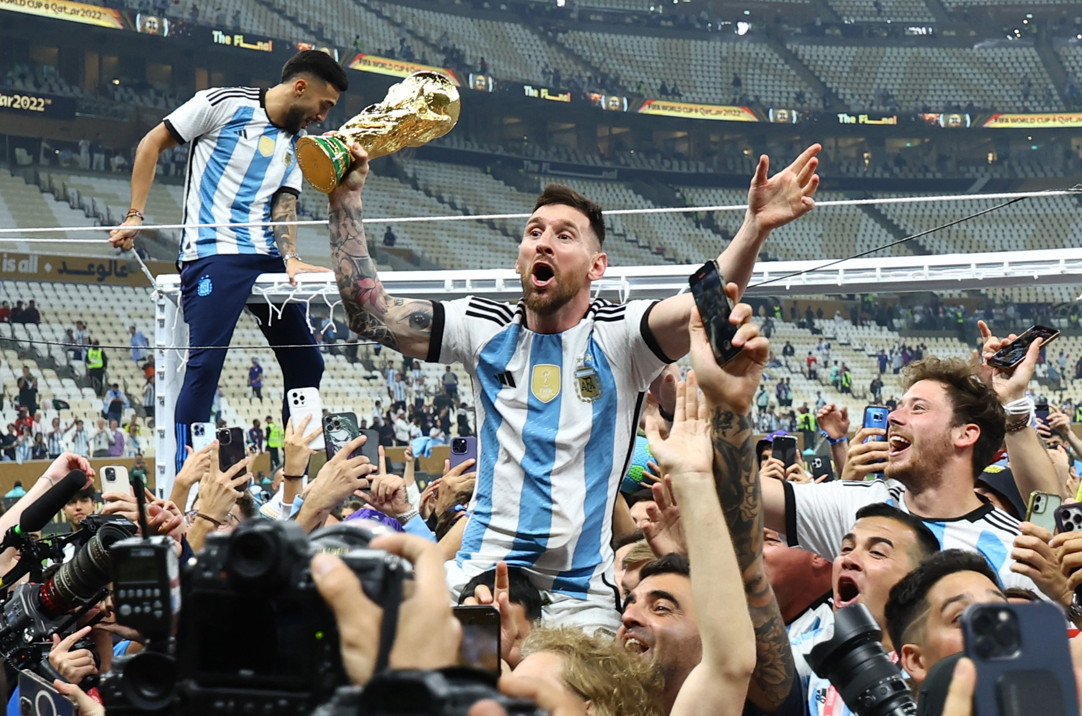 Soccer Football - FIFA World Cup Qatar 2022 - Final - Argentina v France - Lusail Stadium, Lusail, Qatar - December 18, 2022 Argentina's Lionel Messi celebrates with the trophy and fans after winning the World Cup REUTERS/Kai Pfaffenbach
