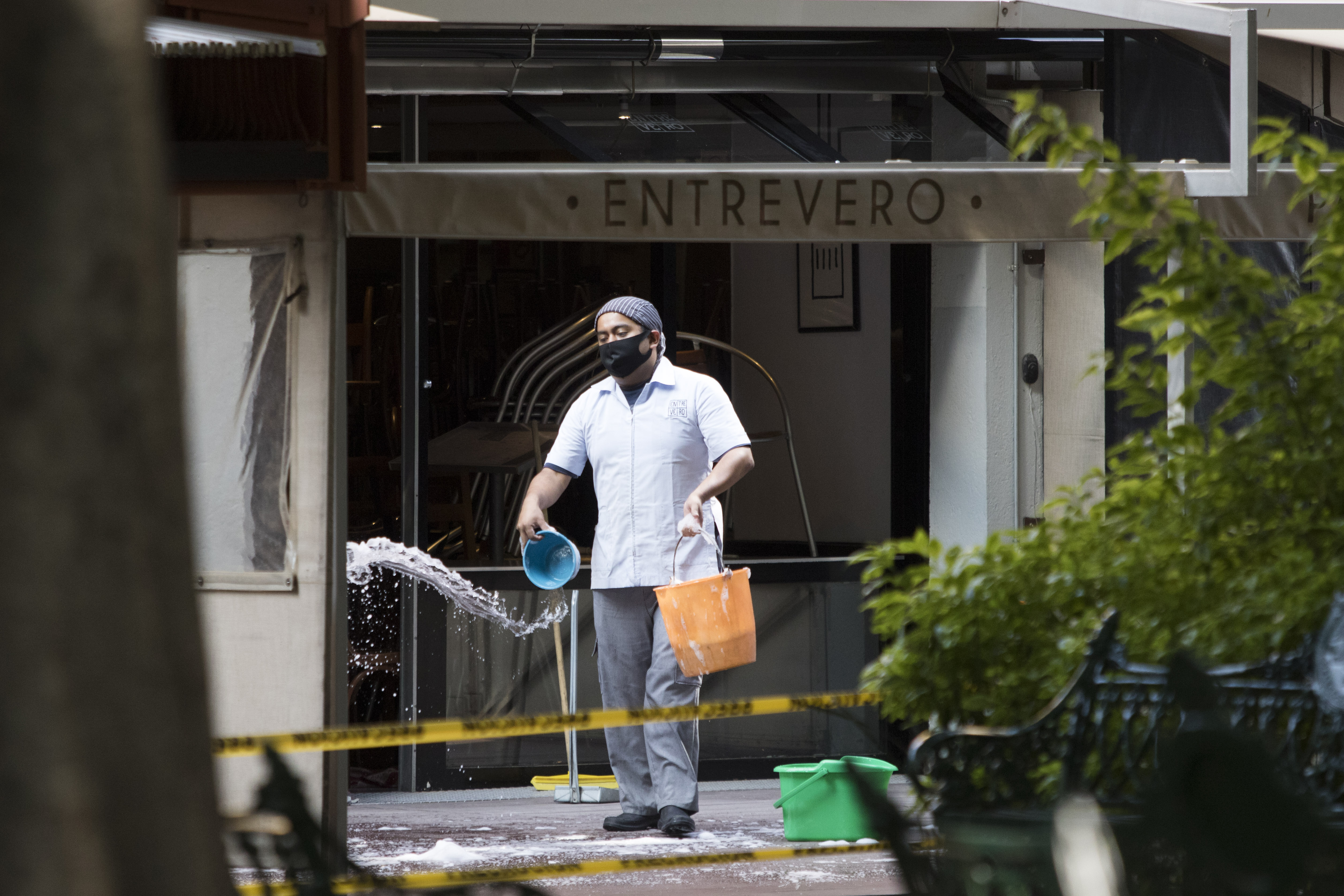 Un trabajador limpia la entrada del restaurante Entrevero en la Ciudad de México, el 1 de julio de 2020 durante la pandemia COVID-19. (Foto: CLAUDIO CRUZ / AFP)