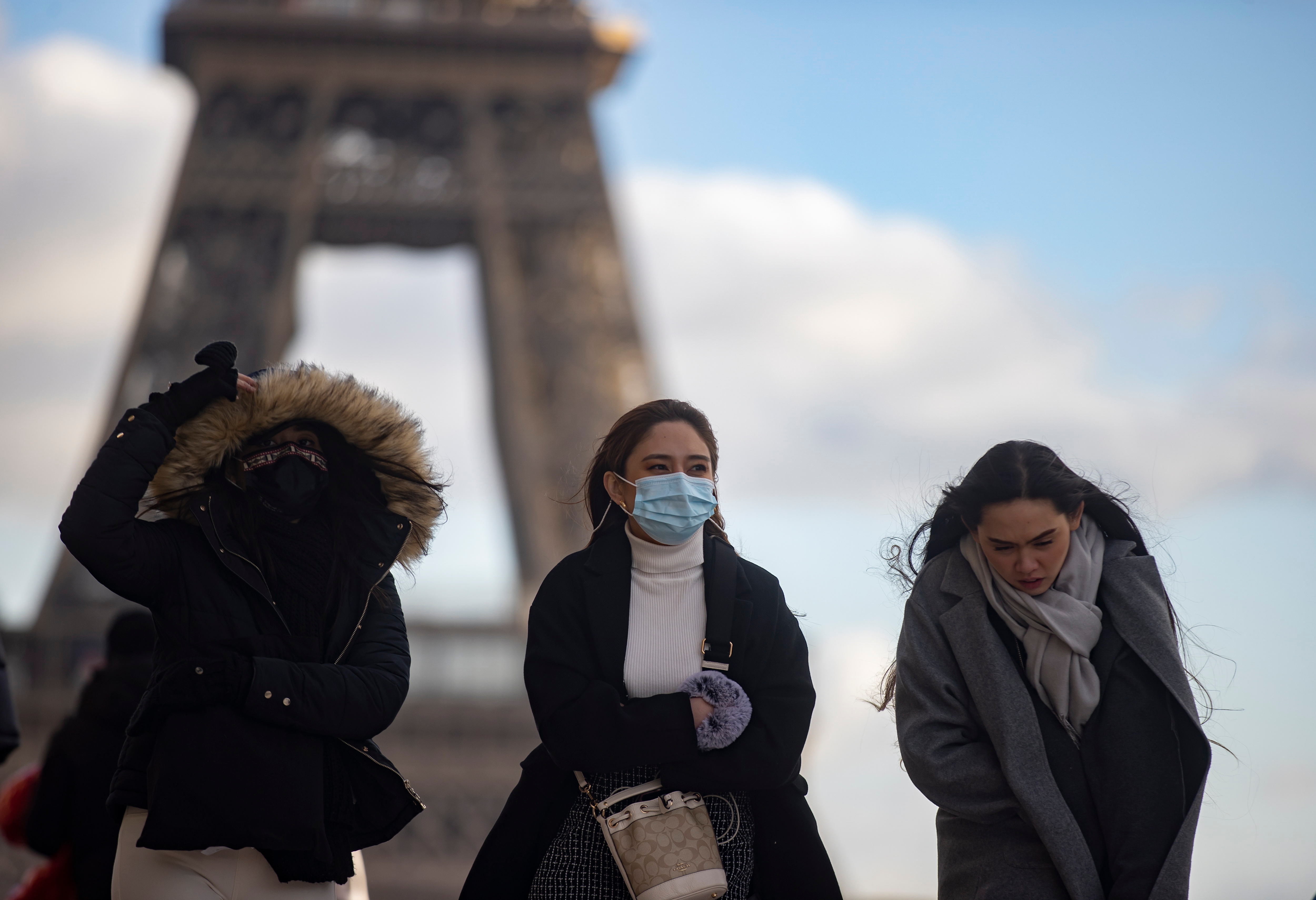 A group of masked young people walk through Paris, with the Eiffel Tower in the background.  EFE/EPA/IAN LANGSDON