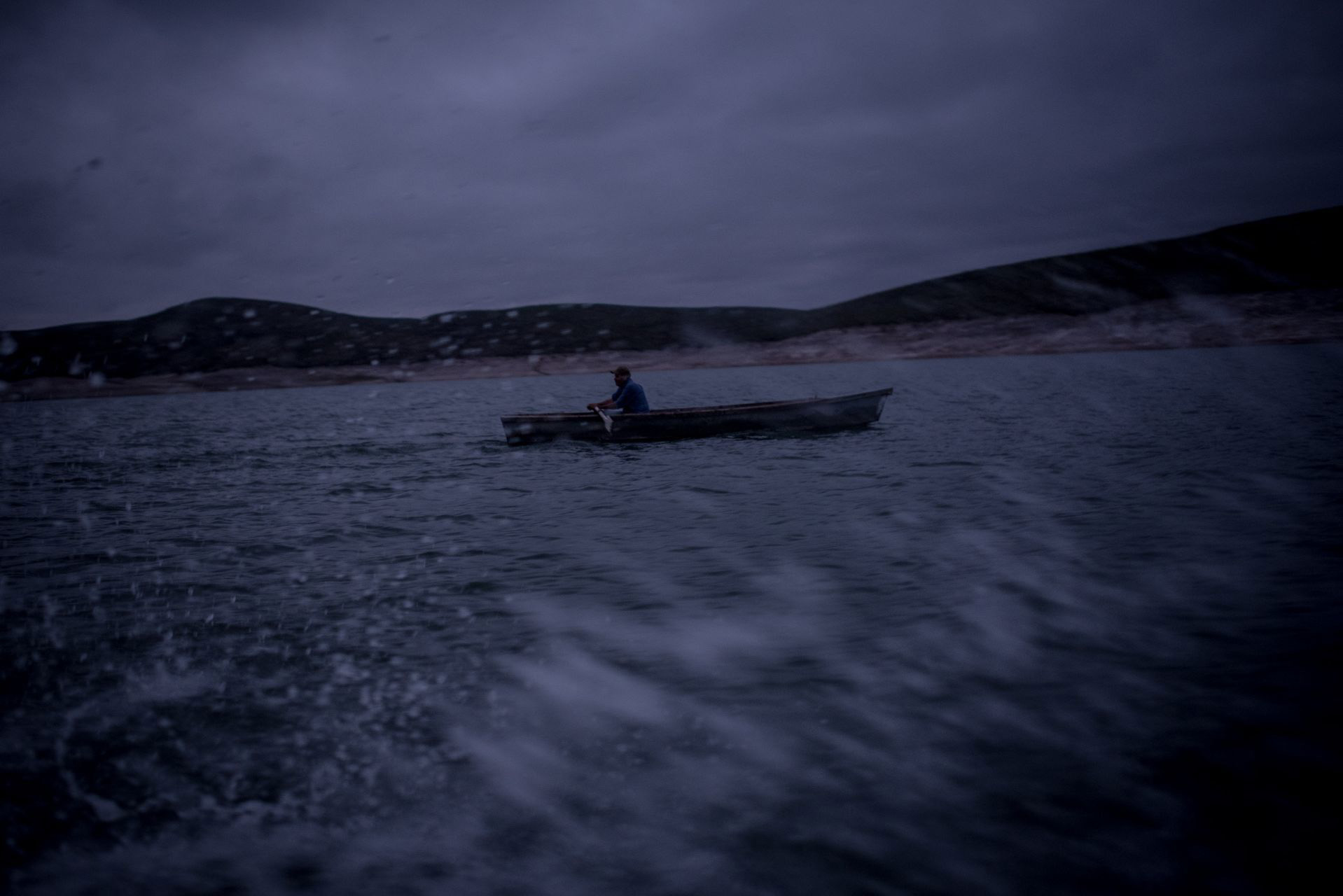 Un pescador avanza al despuntar el día en la presa