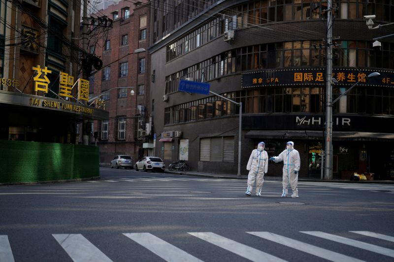 FOTO DE ARCHIVO: Trabajadores con trajes de protección vigilan en una calle durante un confinamiento, durante la pandemia de COVID-19 en Shanghái, China, 16 de abril de 2022. REUTERS/Aly Song