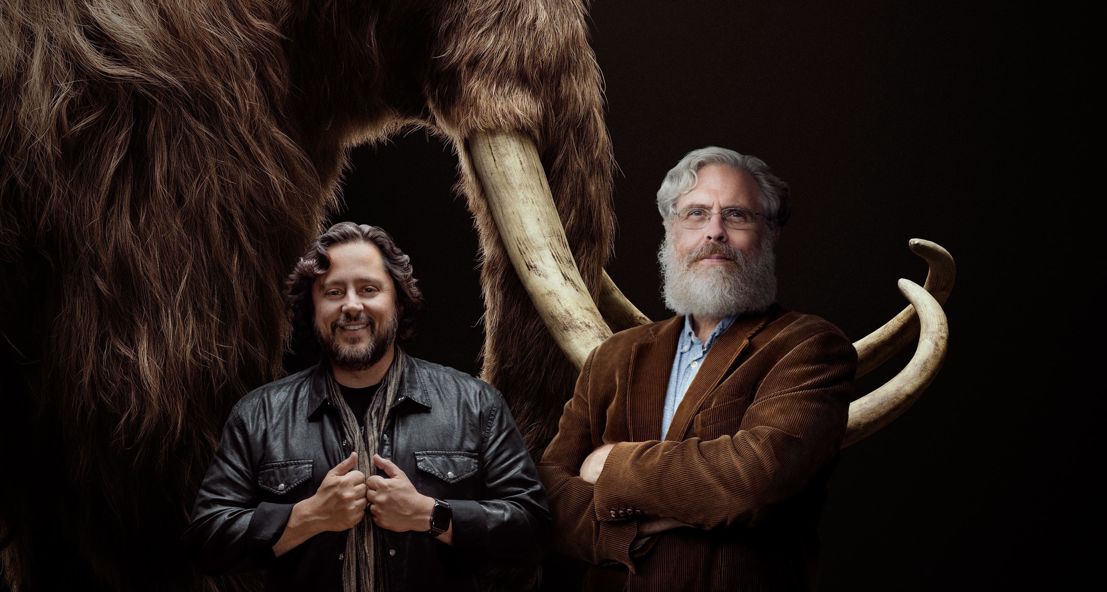 Los cofundadores de Colossal, los empresarios y científicos Ben Lamm y George Church, mientras posan frente a la imagen de un mamut (EFE/Colossal)