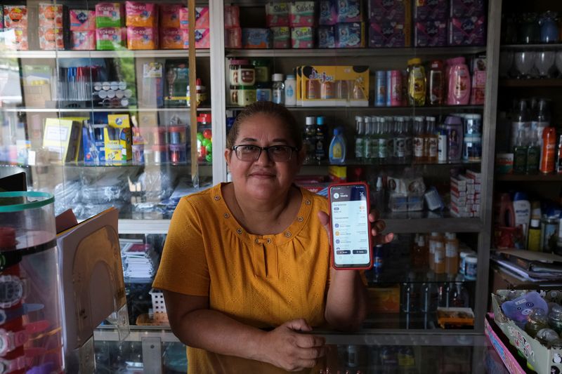 Una vendedora muestra su cartera de Bitcoin en su tienda en la ciudad de Conchagua, cerca del sitio proyectado para la Ciudad Bitcoin en Conchagua (REUTERS/Jose Cabezas)