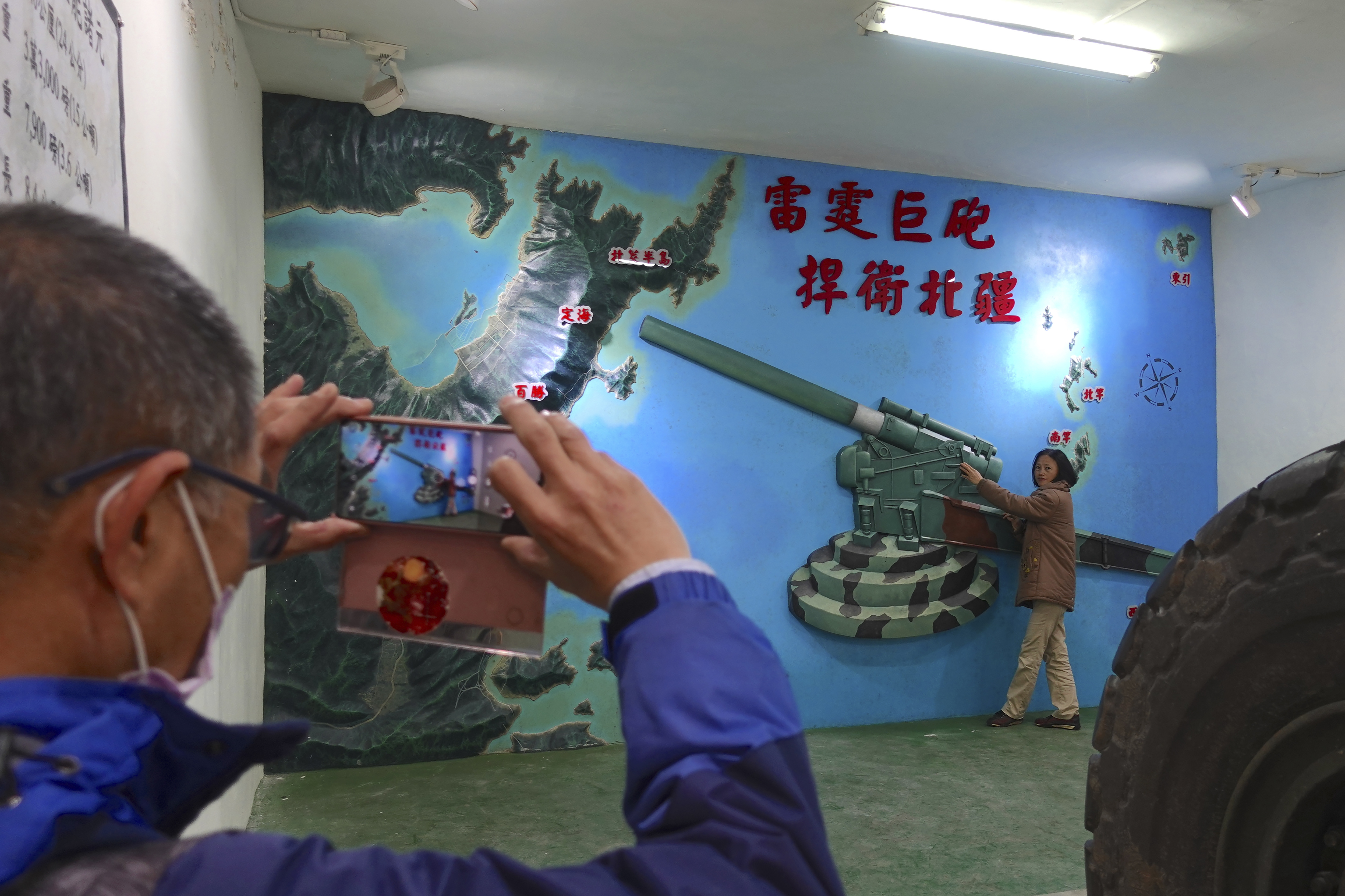 Un turista posa para las fotos cerca de un mural que representa un obús apuntando hacia la provincia de Fujian, en China continental, en una base museo de Nanga. (AP/Johnson Lai)
