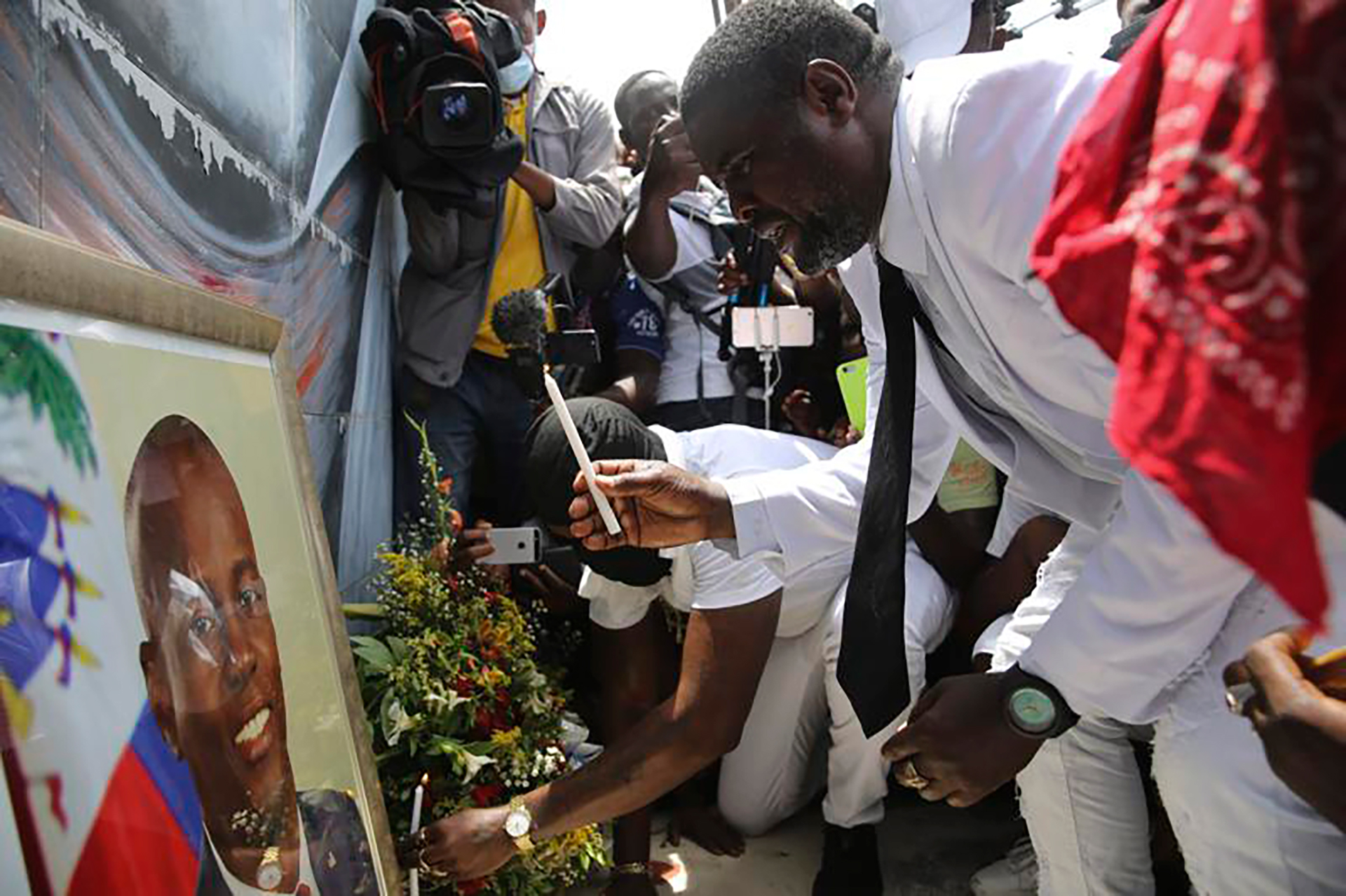 Jimmy "Barbecue" Cherizier prende una vela ante un retrato de Jovenel Moise el lunes 26 de julio en Puerto Príncipe (AP Images)