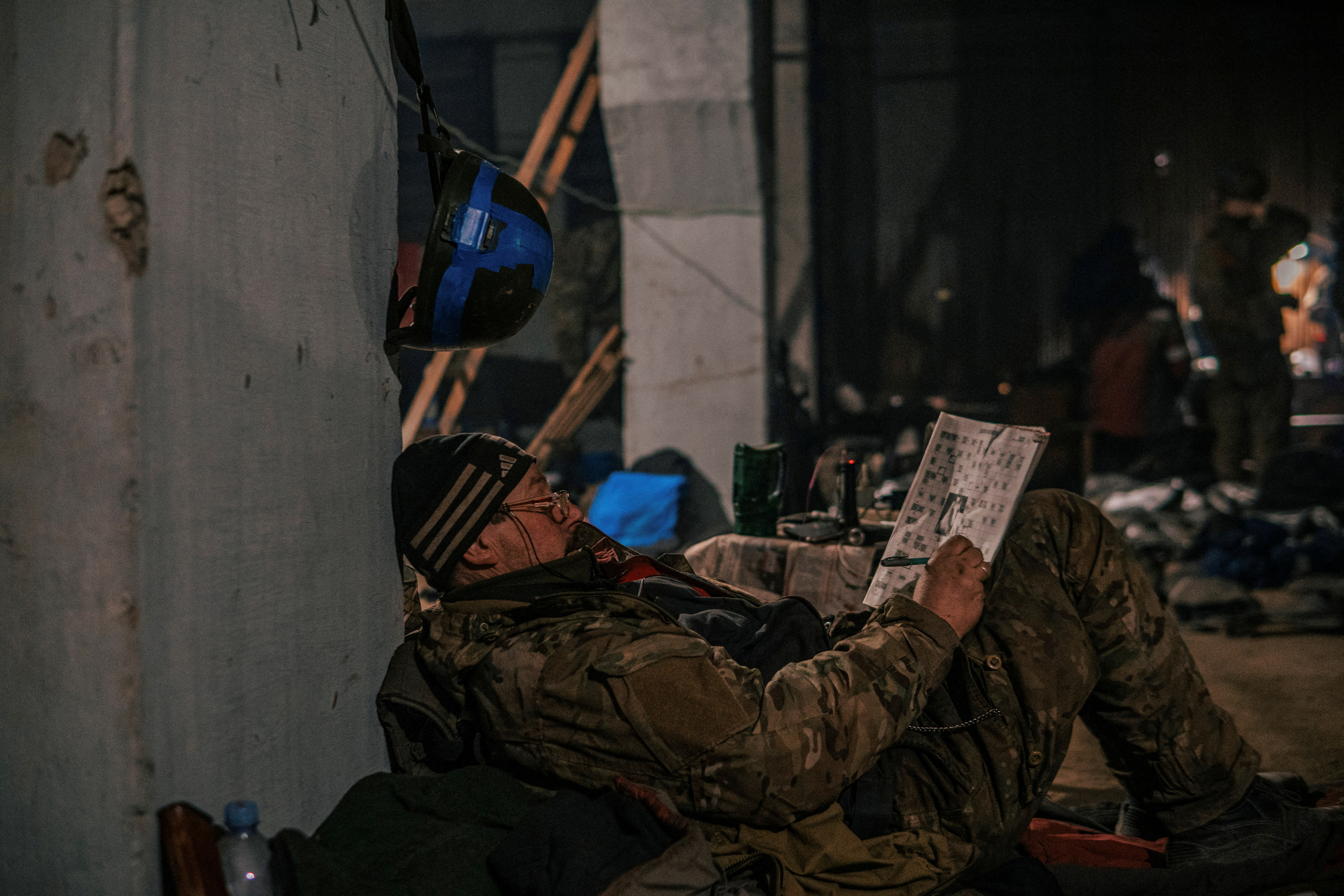 Palabras cruzadas.  Un mimembro del Regimento Azov completes a quadro rodeado en enseres militares in los games acería ucraniana que rus quieren demoler