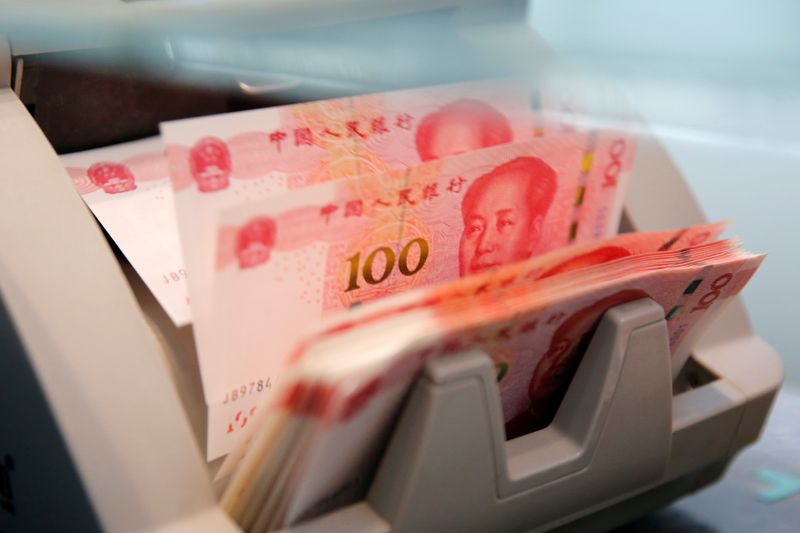 FOTO DE ARCHIVO: Billetes chinos de 100 yuanes en una máquina contadora mientras un empleado los cuenta en una sucursal de un banco comercial en Beijing, China
