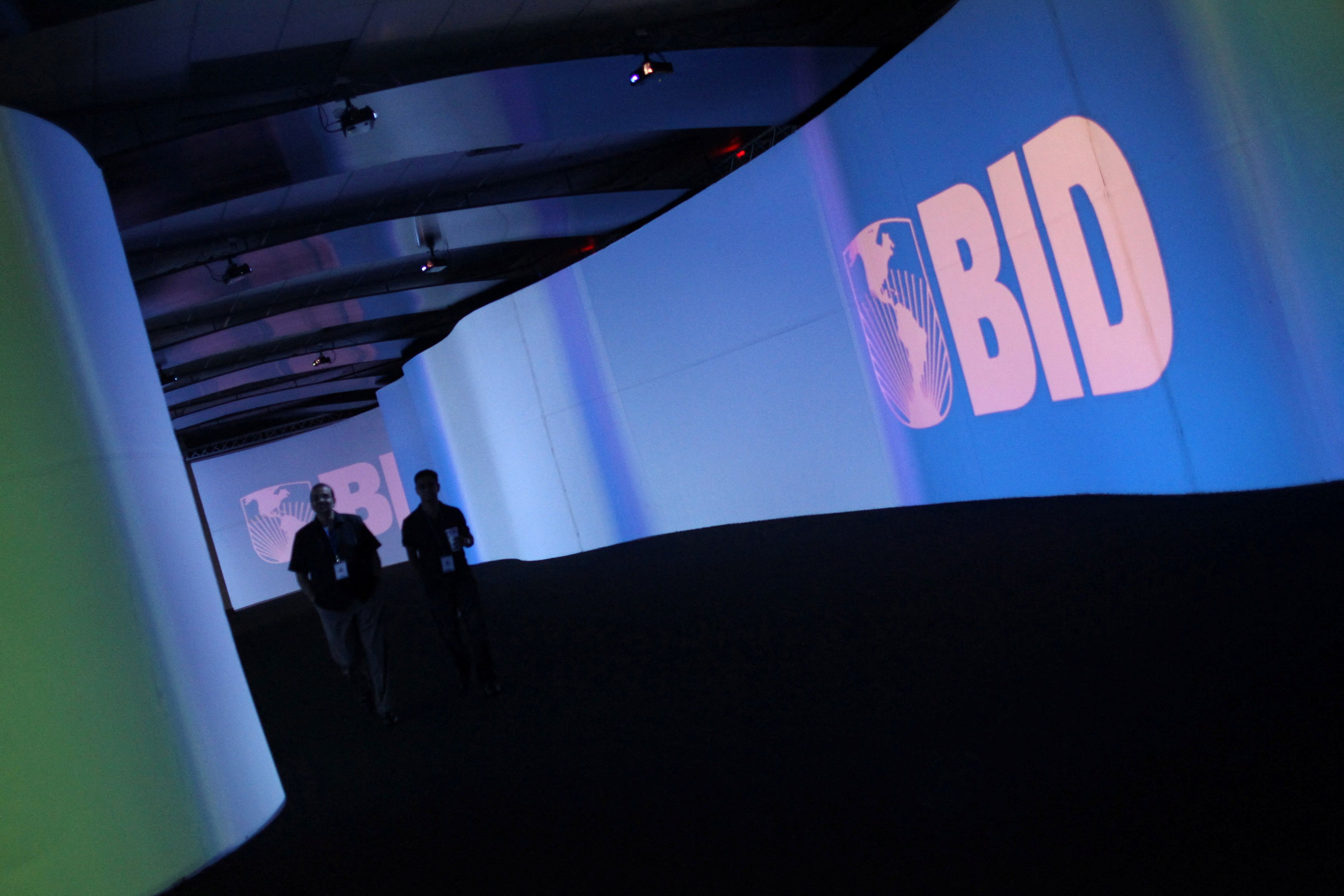 FILE PHOTO: FILE PHOTO: Visitors walk past a screen with the logo of Banco Interamericano de Desarrollo (BID) at the Atlapa Convention Center in Panama City March 13, 2013. Panama will be holding the annual meeting for Boards of Governors of BID, also known as the Inter-American Development Bank (IDB), from March 14 to 17. REUTERS/Carlos Jasso (PANAMA - Tags: BUSINESS LOGO)/File Photo/File Photo