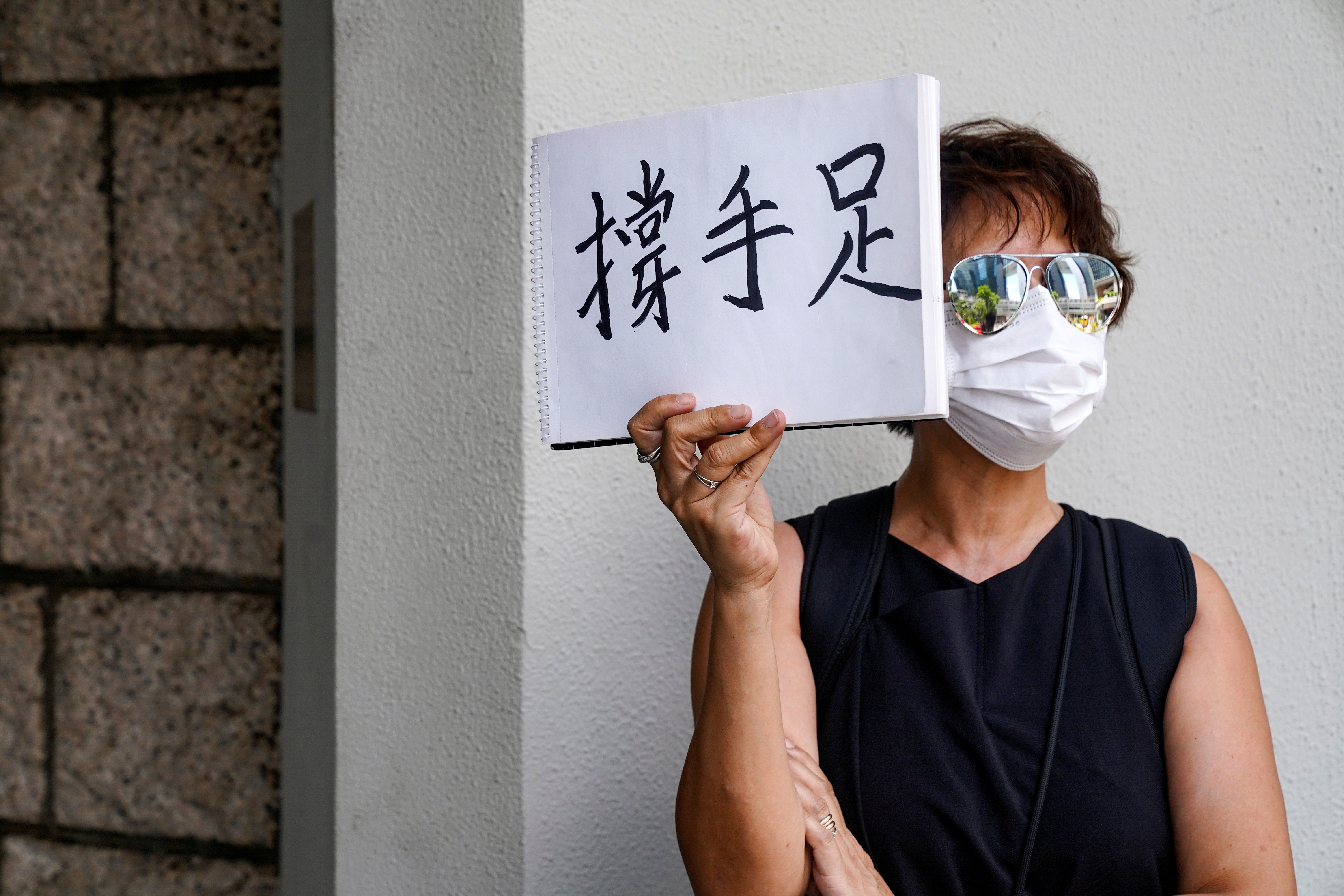 Una mujer sostiene un cartel con la frase "apoyo de hermano" en favor del activista pordemocracia Tong Ying-kit

