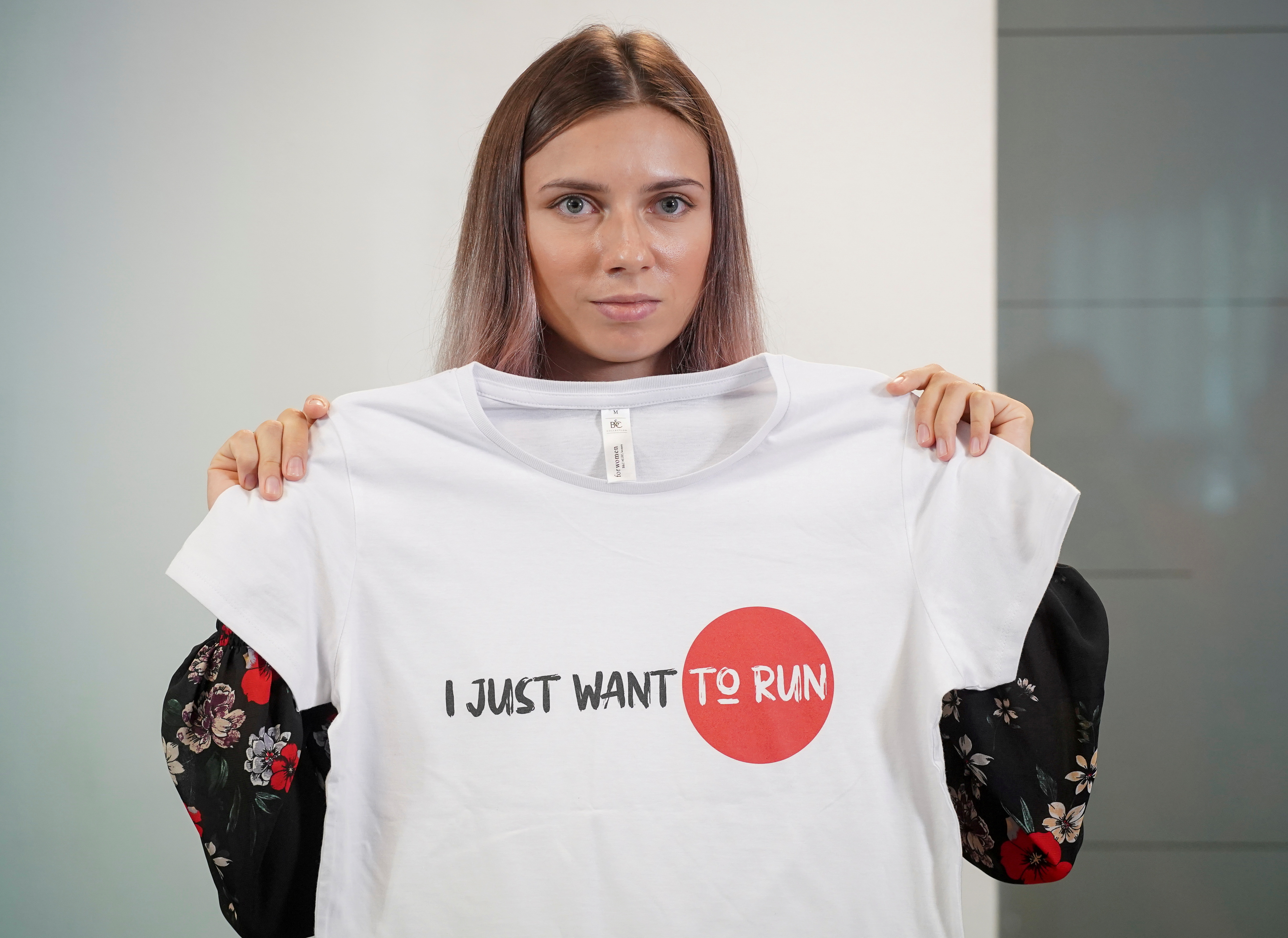 La velocista bielorrusa Krystsina Tsimanouskaya, que abandonó los Juegos Olímpicos de Tokio y buscó asilo en Polonia, sostiene una camiseta en una rueda de prensa en Varsovia (Foto: REUTERS)