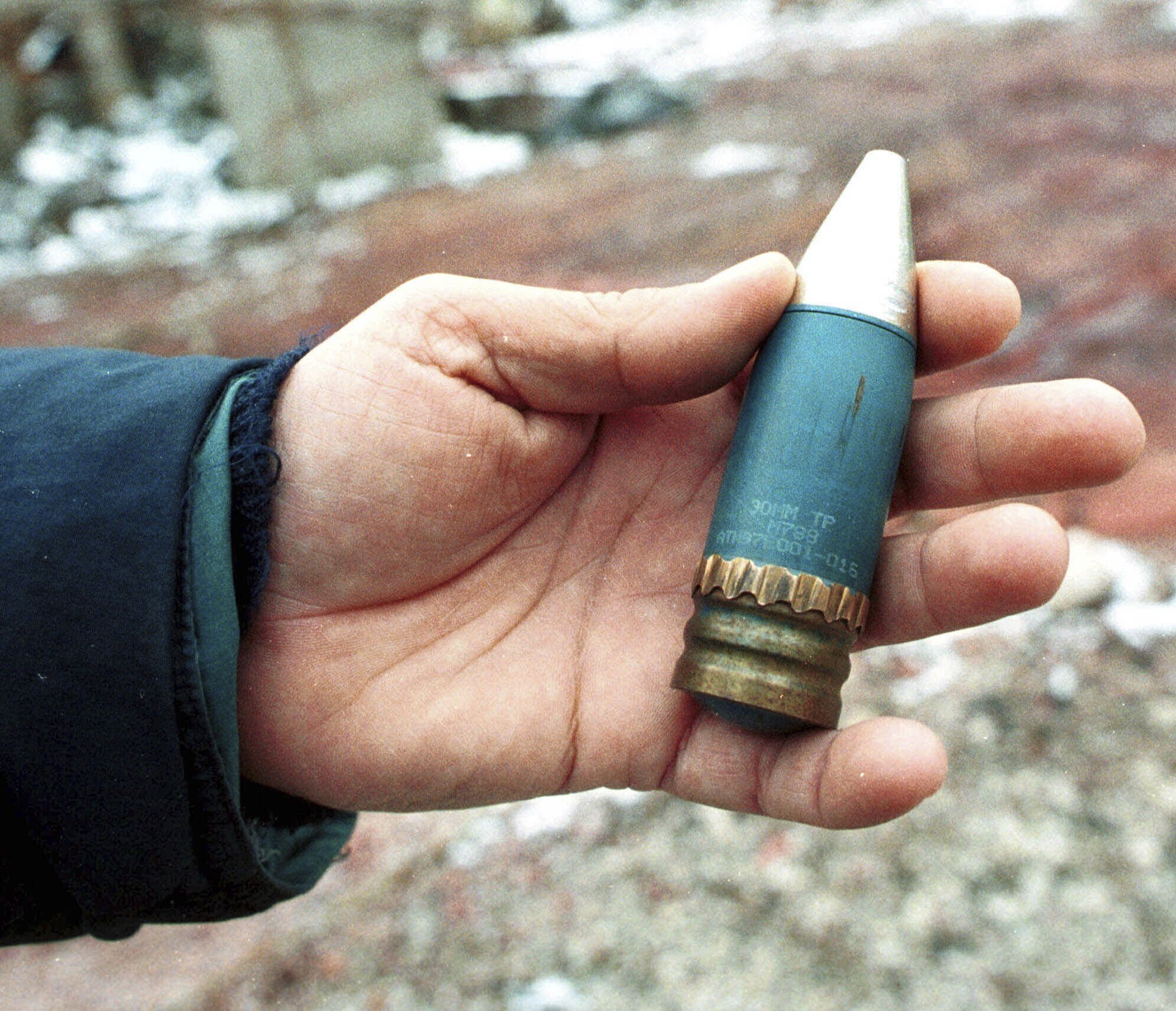 Un miembro de un equipo de especialistas en radiación sostiene un proyectil perforante de 30 mm que contiene uranio empobrecido, utilizado por la OTAN durante los ataques aéreos contra Bosnia en 1995, y que fue hallado en una antigua fábrica militar en el suburbio de Vogosca, cerca de Sarajevo, el 15 de enero de 2001. (AP Foto/Hidajet Delic, Archivo)