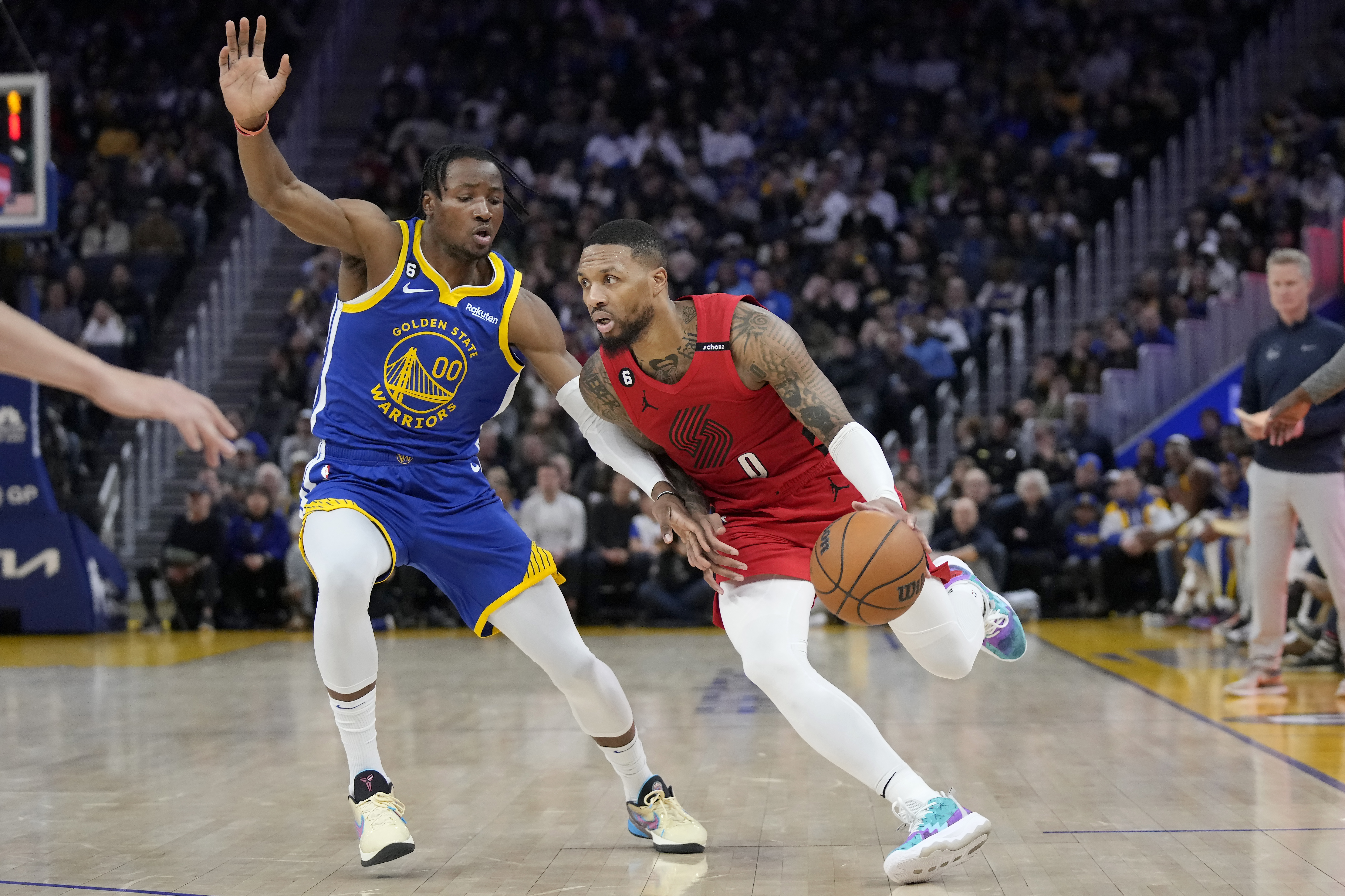 El jugador de los Trail Blazers de Portland Damian Lillard (0) conduce la pelota ante su rival de los Warriors de Golden State Jonathan Kuminga (00), en la primera mitad del juego de la NBA que enfrentaron a ambos equipos, en San Francisco, el 28 de febrero de 2023. (AP Foto/Jeff Chiu)