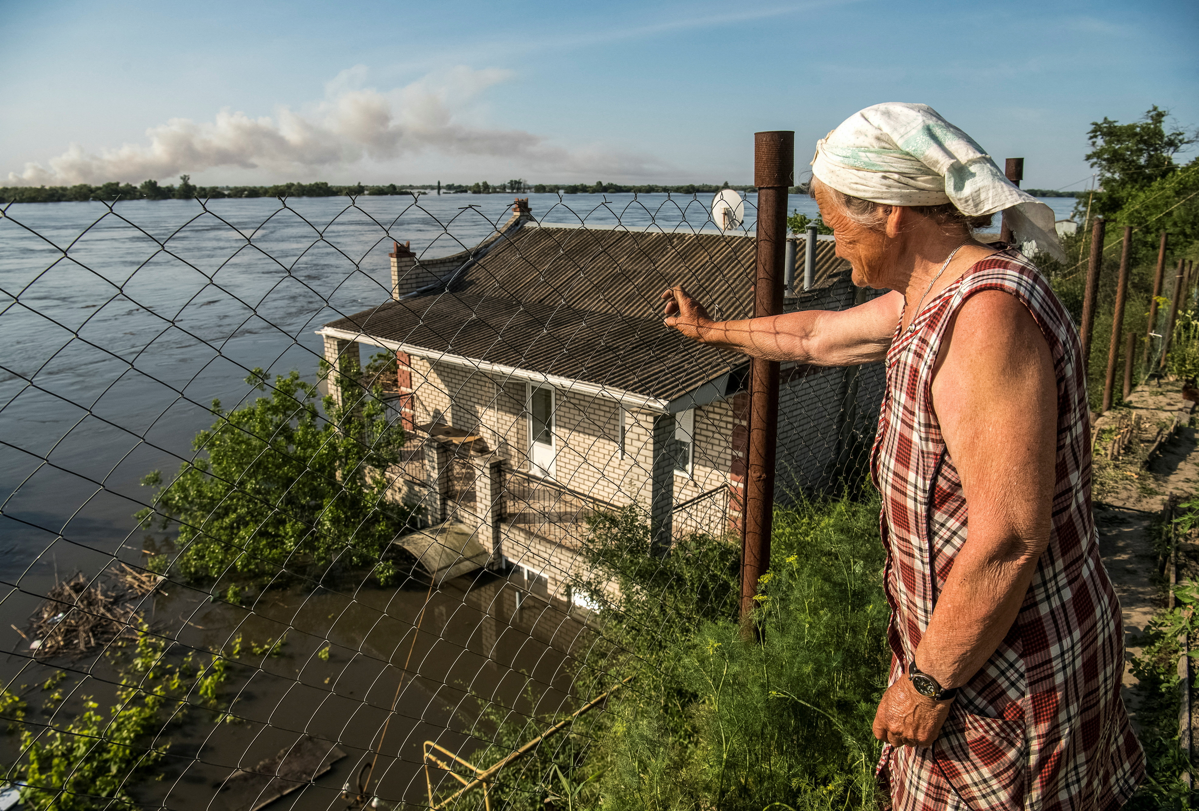 Una mujer mira como su casa es alcanzada por el agua.