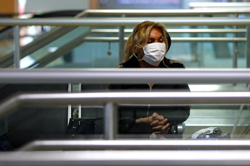 gambar stok.  Orang-orang mengenakan masker pelindung di Bandara Internasional Jorge Chavez di Lima.  Foto: Sebastian Castaneda/Reuters.