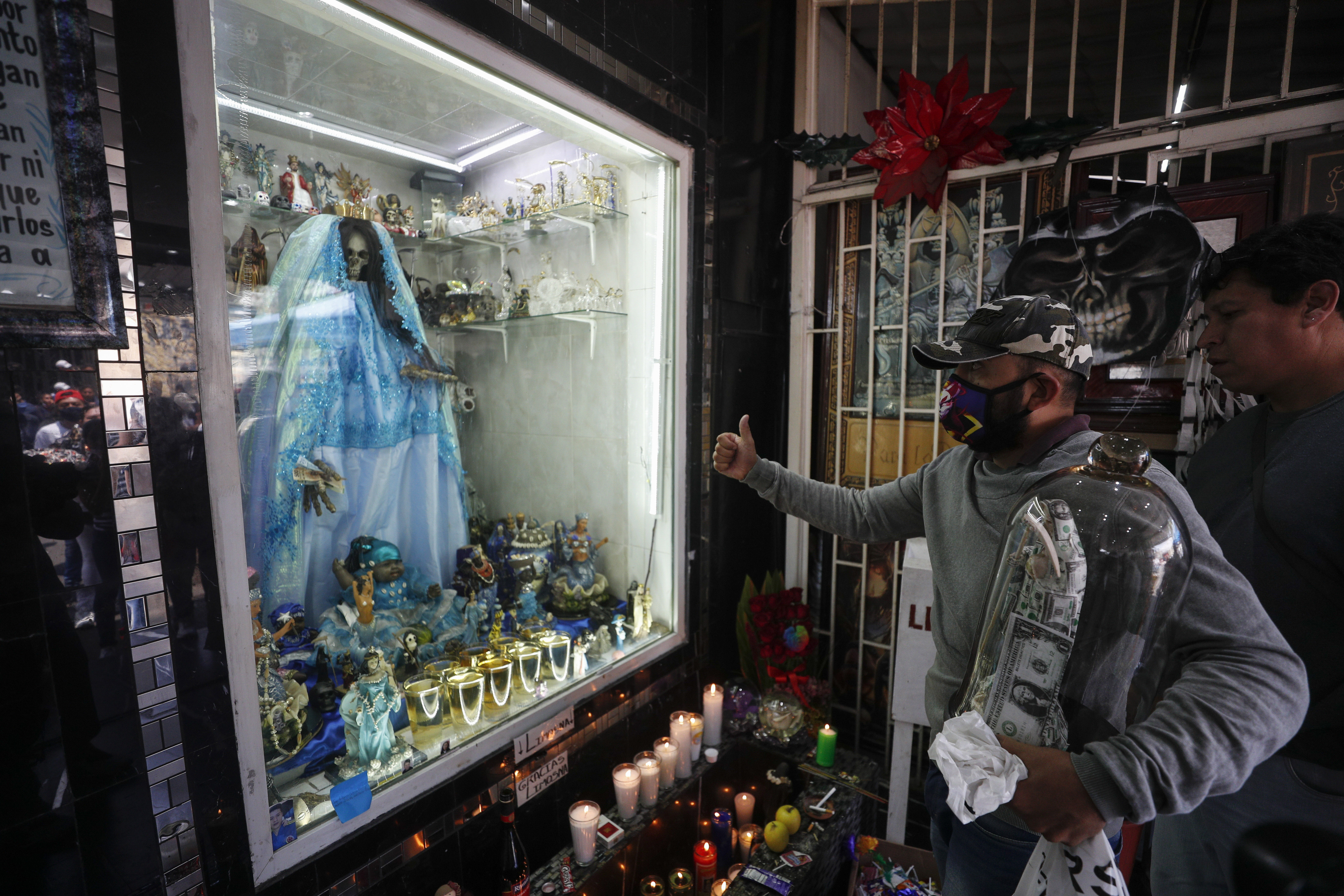 Un devoto de Santa Muerte da un pulgar hacia arriba mientras le presenta sus respetos en un altar en el barrio de Tepito. (Foto: AP / Rebecca Blackwell)