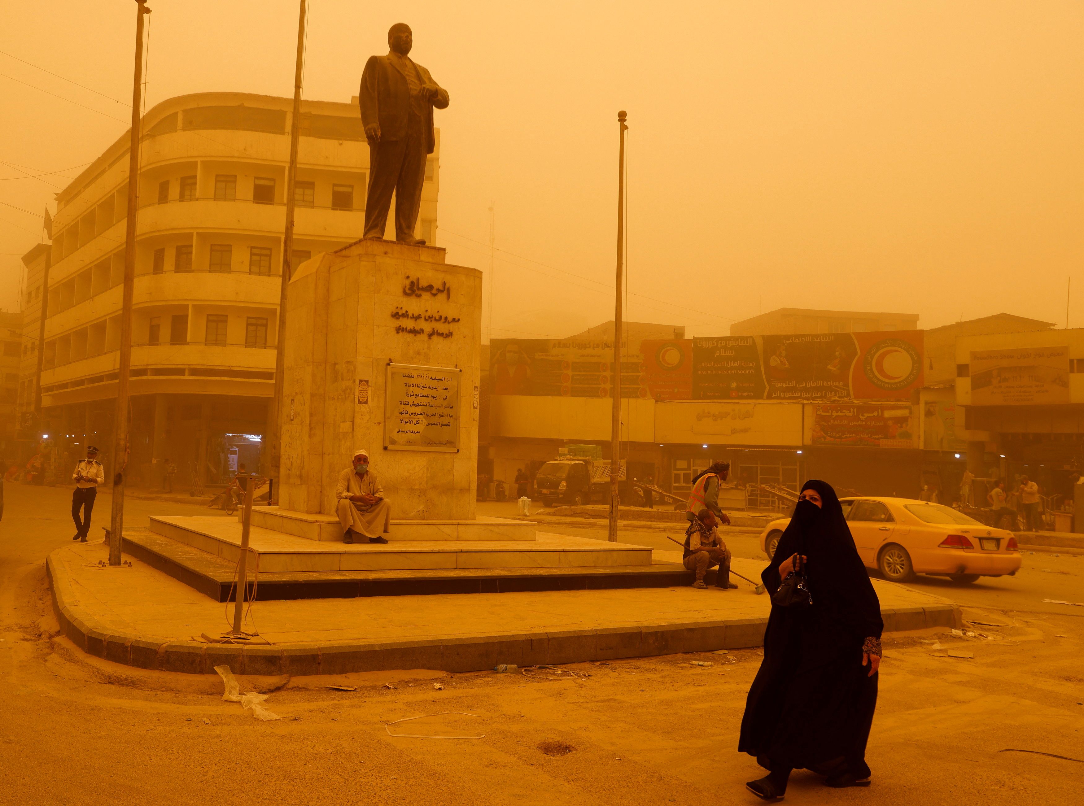Una mujer pasa junto a una estatua del poeta iraquí Abdel Ghani Maarouf al Rusafi durante una tormenta de arena en Bagdad, Irak, el 16 de mayo de 2022. REUTERS/Ahmed Saad
